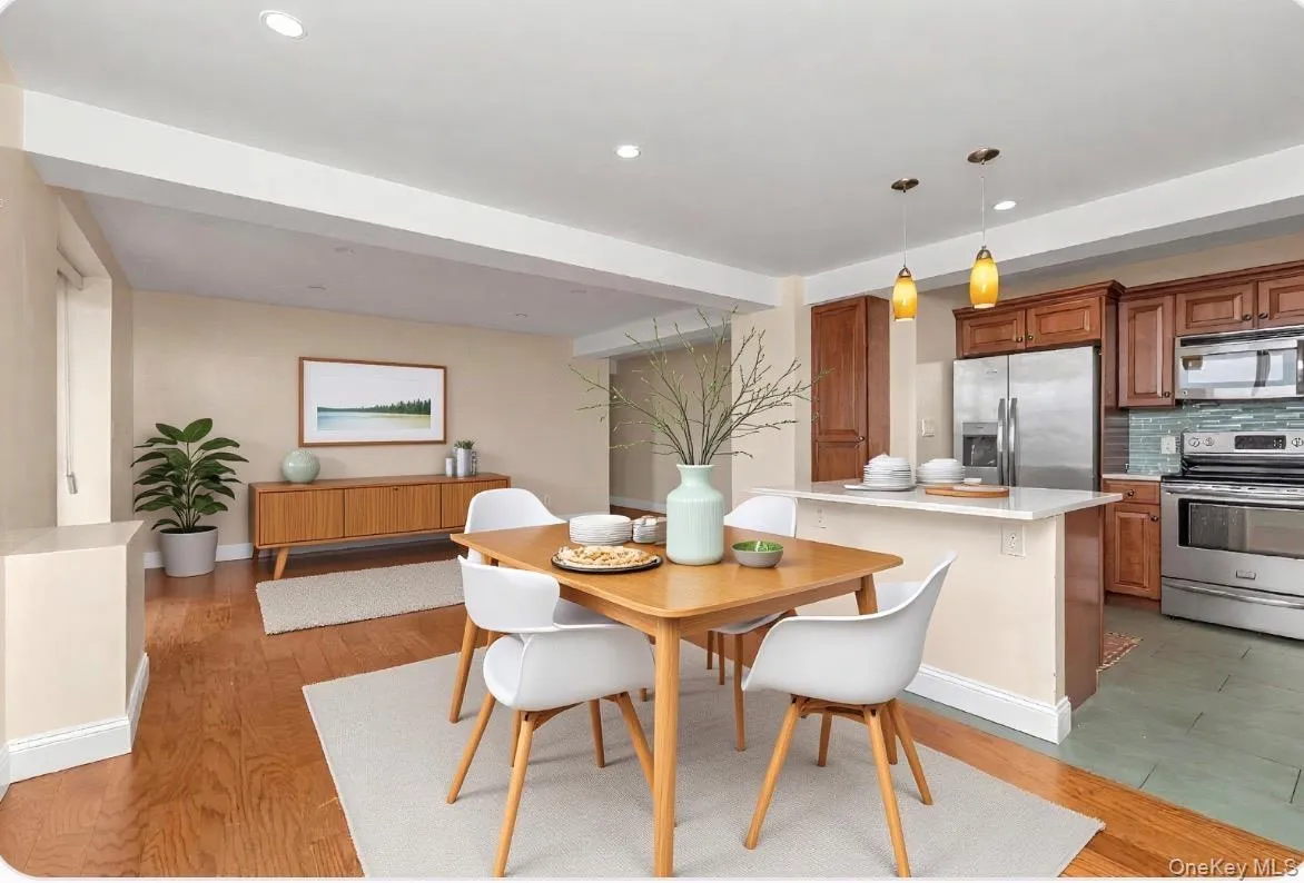 Open-concept dining and kitchen area featuring warm wood-finish flooring in the dining space Open-concept dining and kitchen area featuring warm wood-finish flooring in the dining space