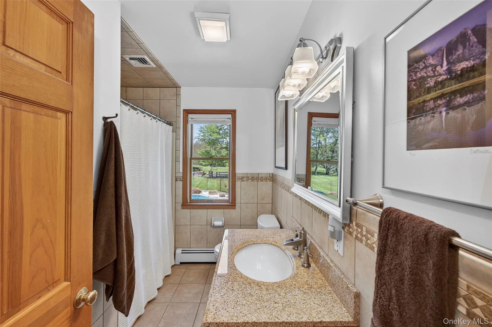 Main floor full bathroom featuring tile with decorative border and granite counter Main floor full bathroom featuring tile with decorative border and granite counter