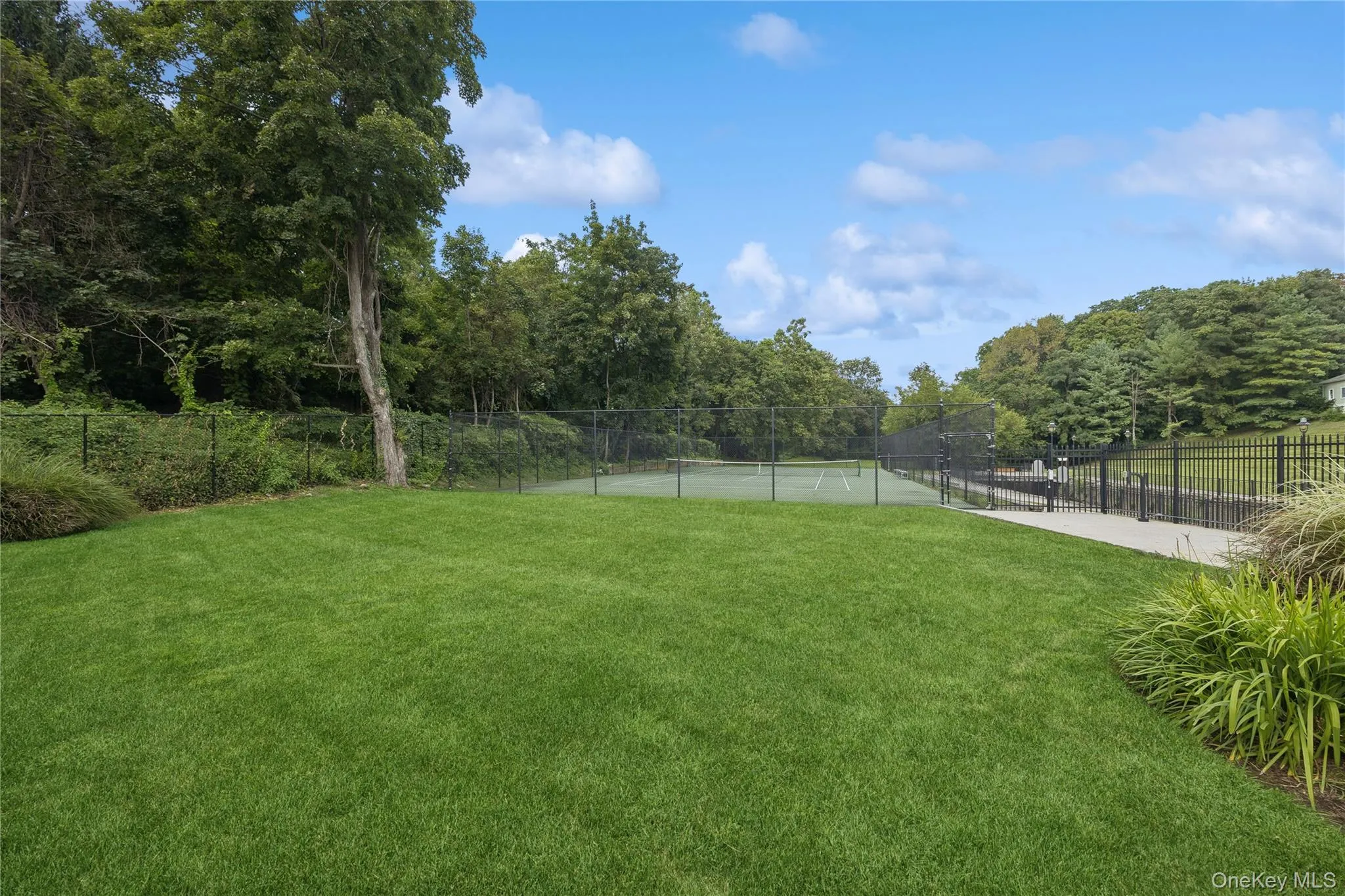 View of the expansive green space with tennis court. View of the expansive green space with tennis court.
