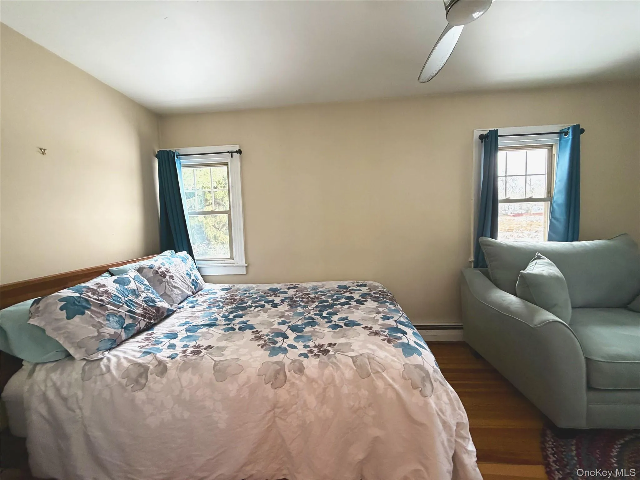Bedroom with dark wood finished floors and a baseboard heating unit Bedroom with dark wood finished floors and a baseboard heating unit