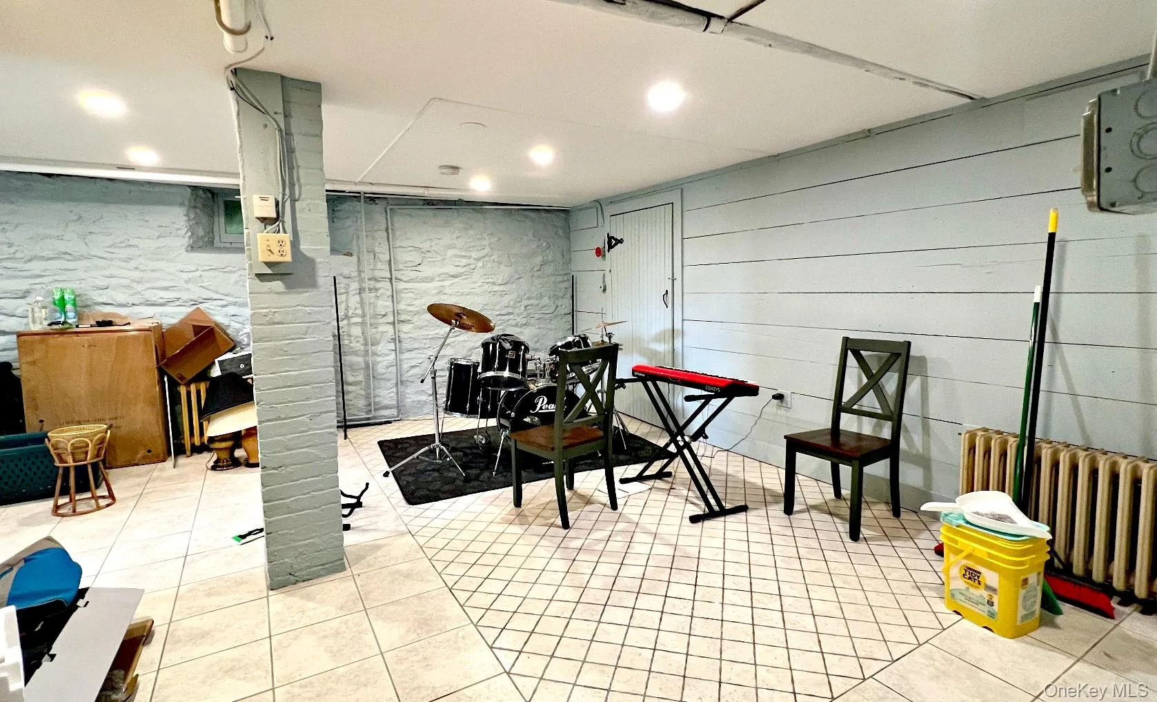 Misc room with radiator heating unit, light tile patterned floors, recessed lighting, and wood walls Misc room with radiator heating unit, light tile patterned floors, recessed lighting, and wood walls