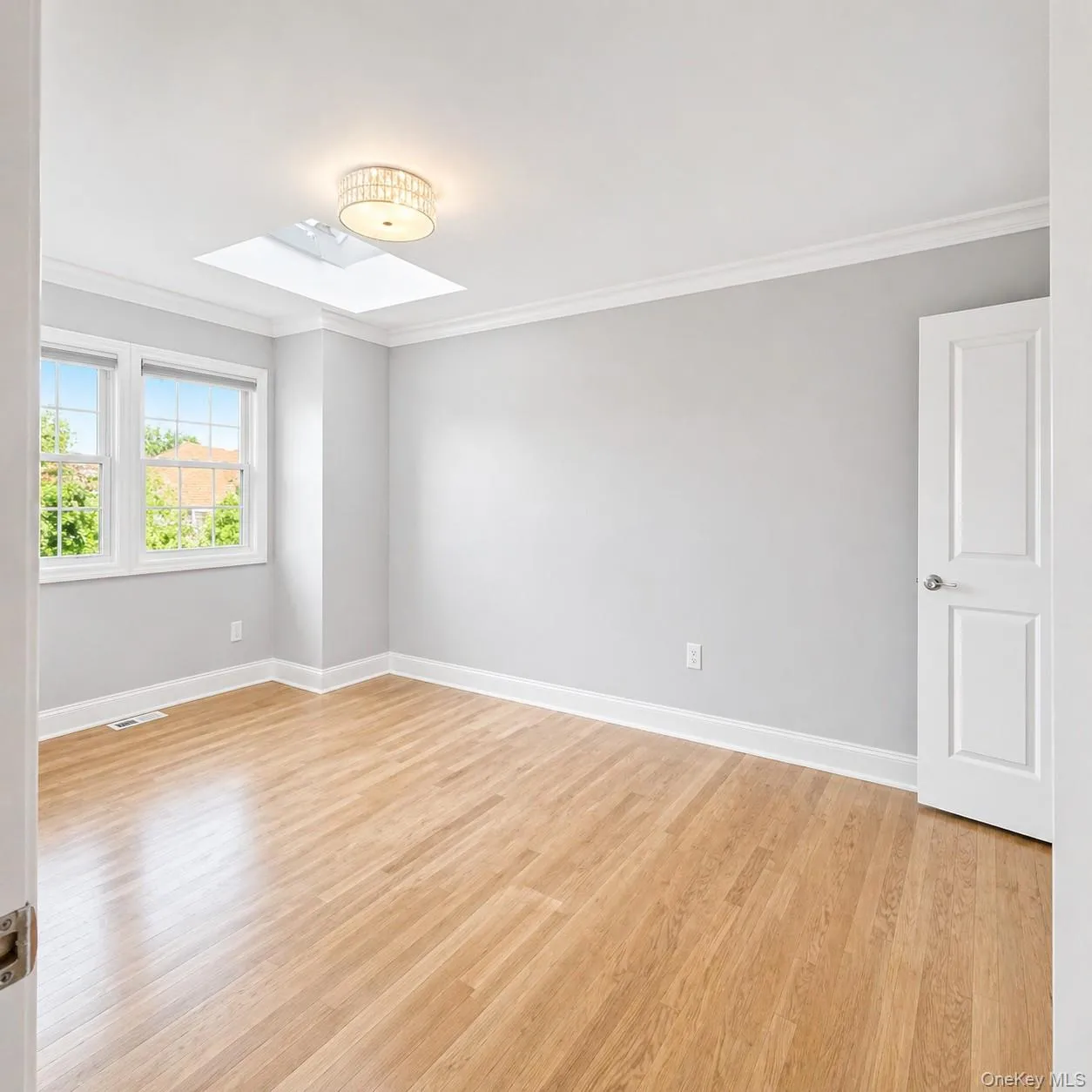 Primary Bedroom with a Large Walk in Closet, Skylight, Wood Flooring, and Crown Molding Primary Bedroom with a Large Walk in Closet, Skylight, Wood Flooring, and Crown Molding