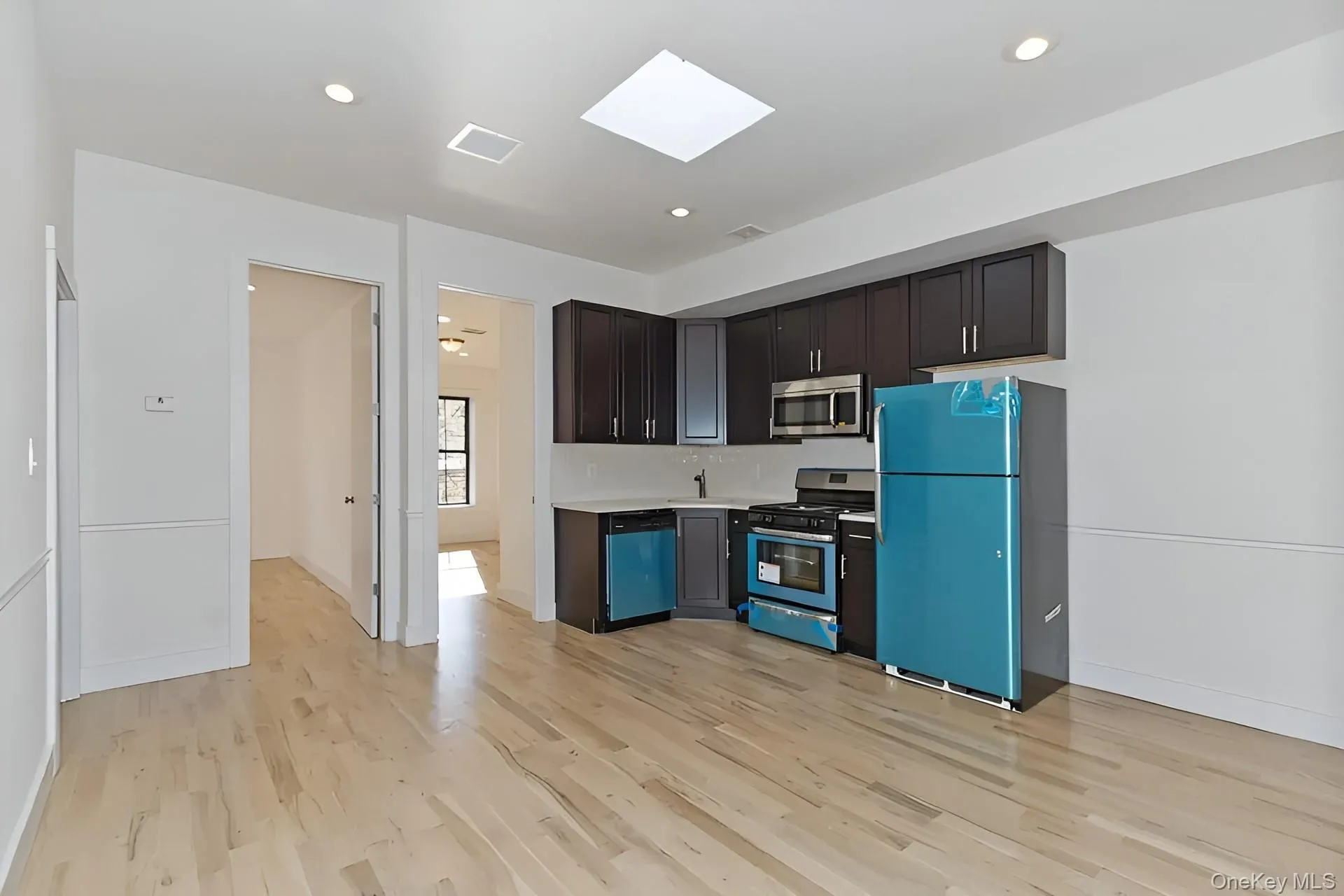 Open-concept living space with light wood-finish flooring, recessed lighting, and a skylight Open-concept living space with light wood-finish flooring, recessed lighting, and a skylight