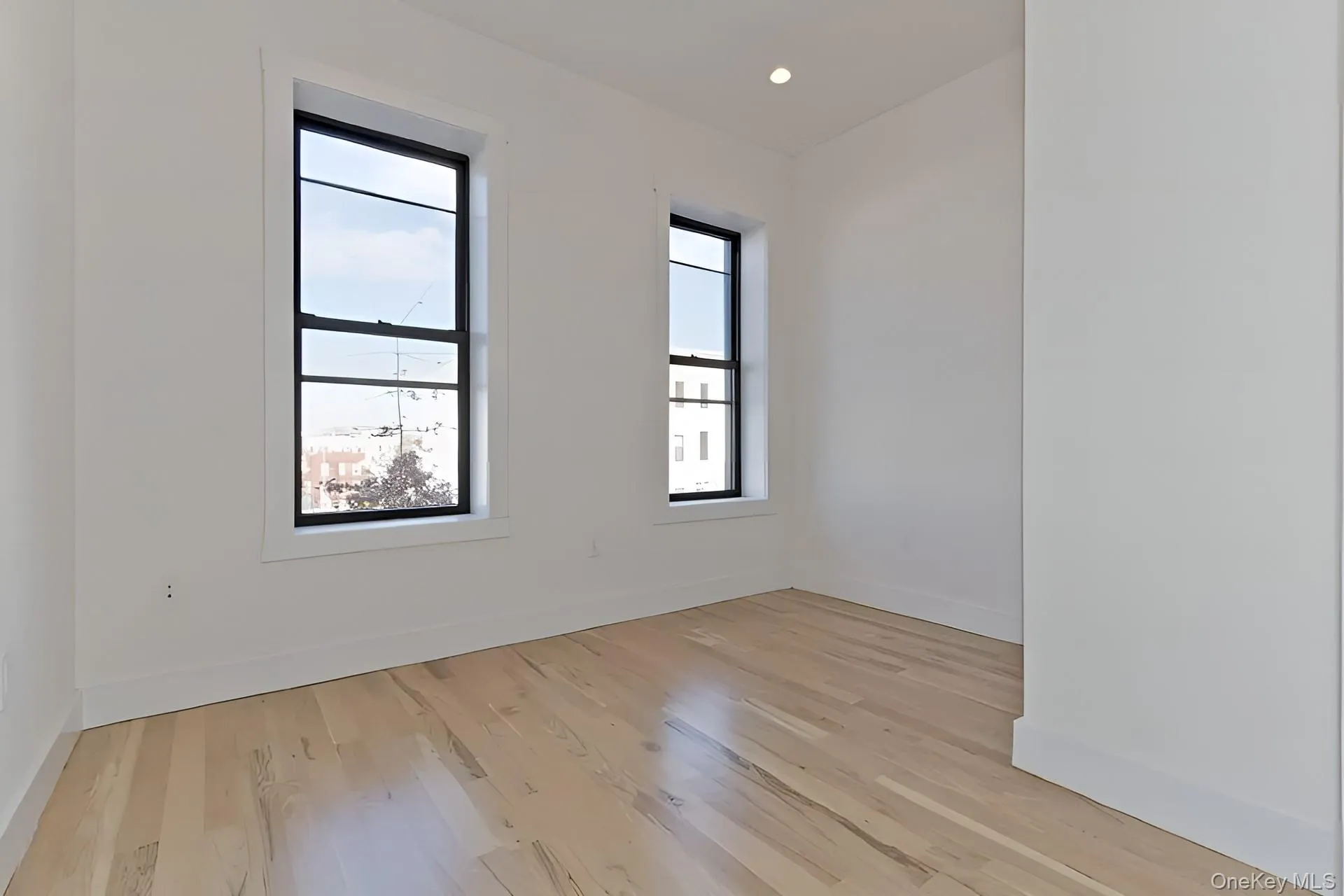 Bright room featuring two large windows with black frames, offering ample natural illumination Bright room featuring two large windows with black frames, offering ample natural illumination