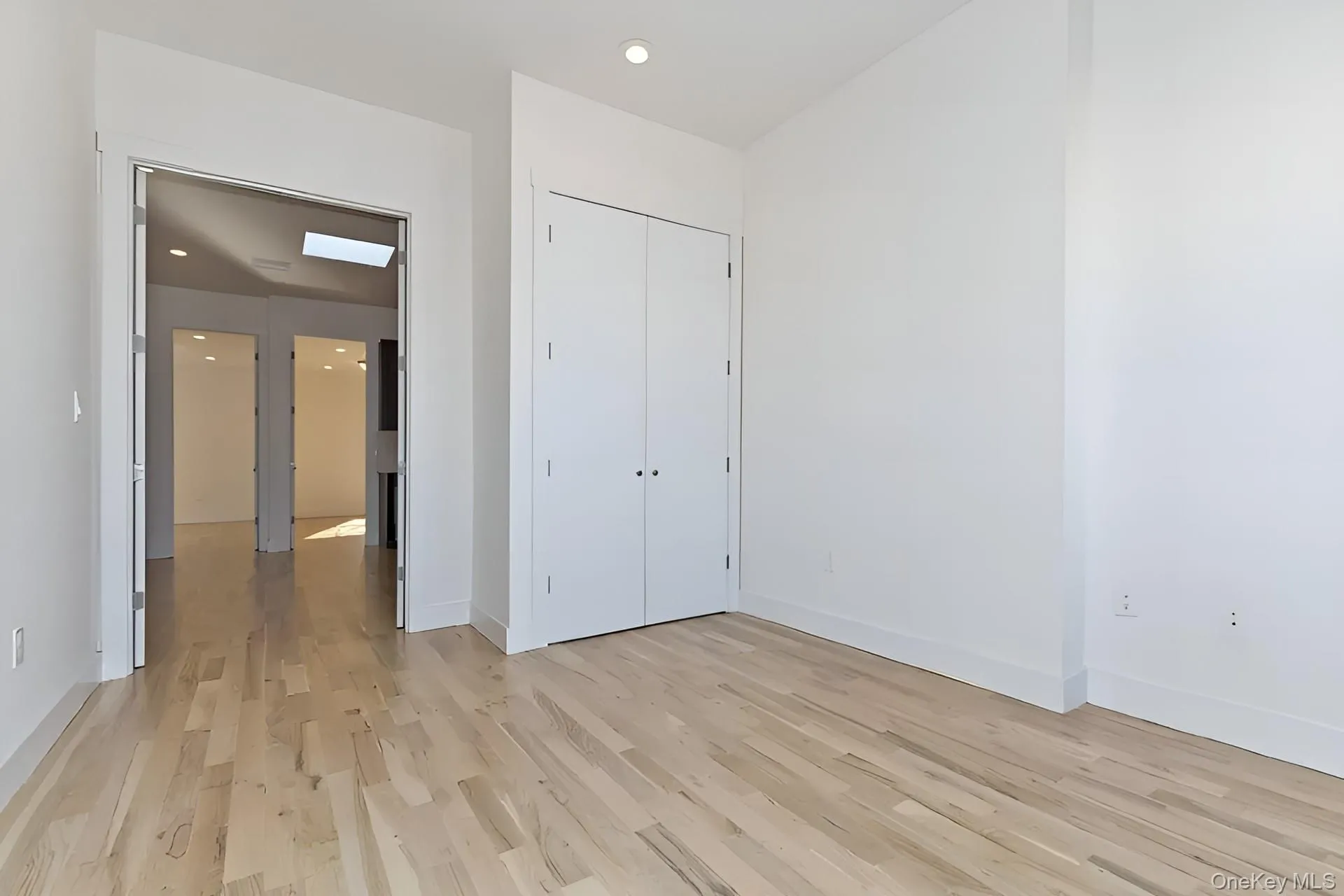 Light wood-finish flooring throughout, featuring a recessed ceiling light and tall baseboards Light wood-finish flooring throughout, featuring a recessed ceiling light and tall baseboards