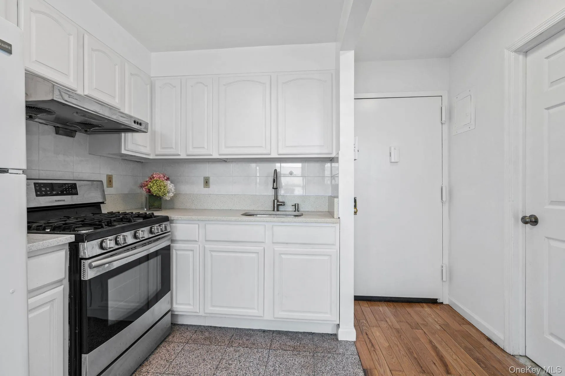 Kitchen with white cabinetry, sink, tasteful backsplash, and gas stove Kitchen with white cabinetry, sink, tasteful backsplash, and gas stove