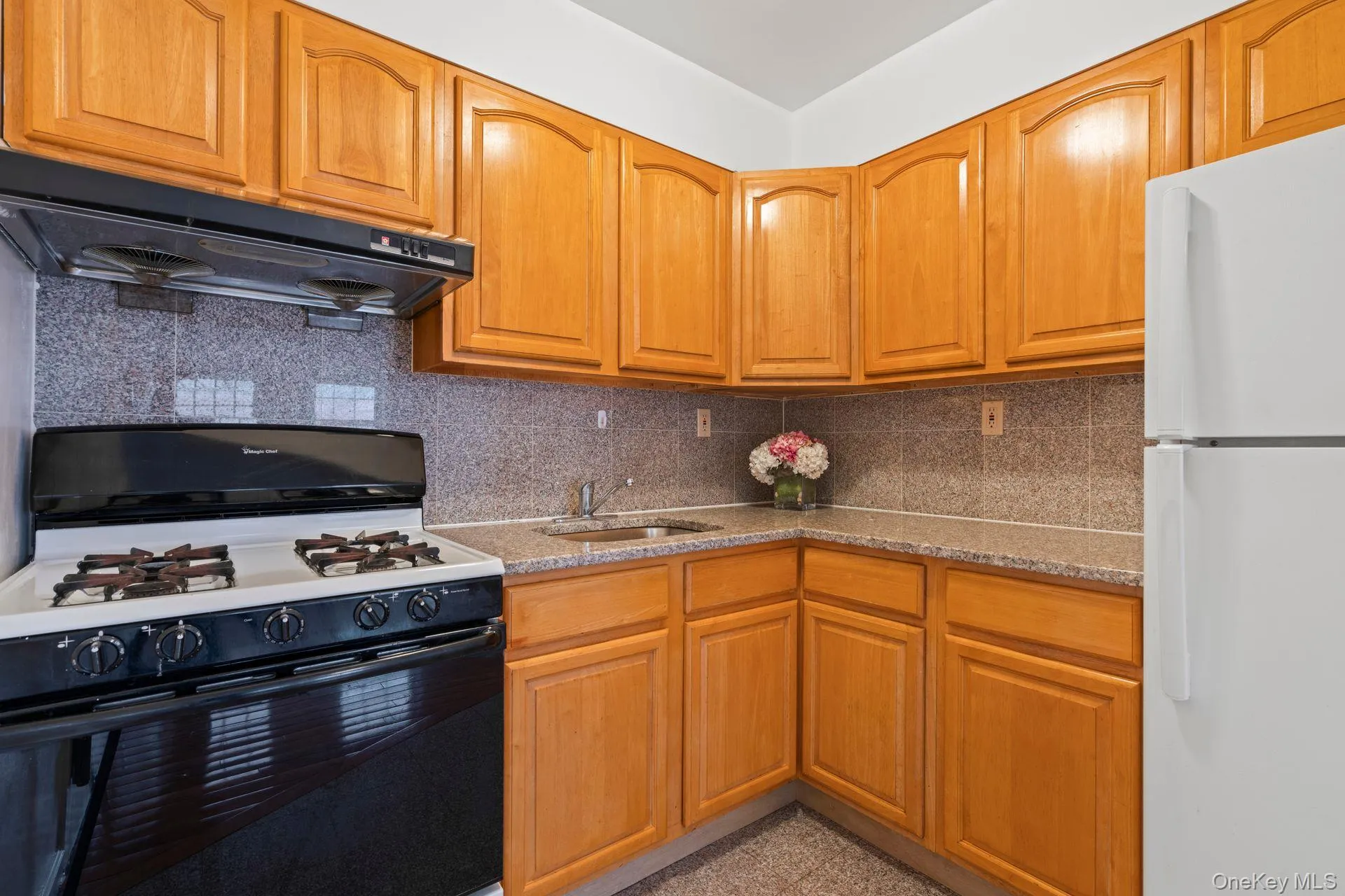 Kitchen featuring sink, gas stove, tasteful backsplash, white fridge, and range hood Kitchen featuring sink, gas stove, tasteful backsplash, white fridge, and range hood