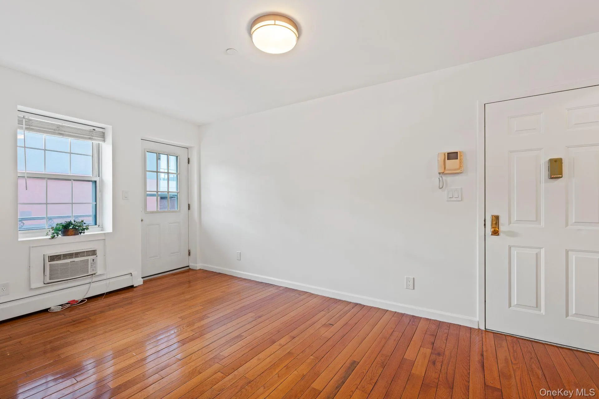 Entrance foyer featuring a baseboard heating unit, hardwood / wood-style flooring, and a wall mounted AC Entrance foyer featuring a baseboard heating unit, hardwood / wood-style flooring, and a wall mounted AC