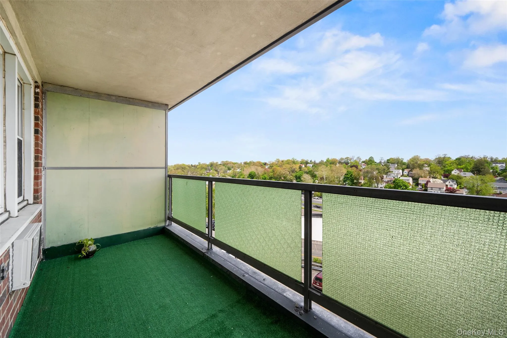 Balcony facing North East ,featuring a green artificial turf floor and a metal railing with frosted glass panels Balcony facing North East ,featuring a green artificial turf floor and a metal railing with frosted glass panels