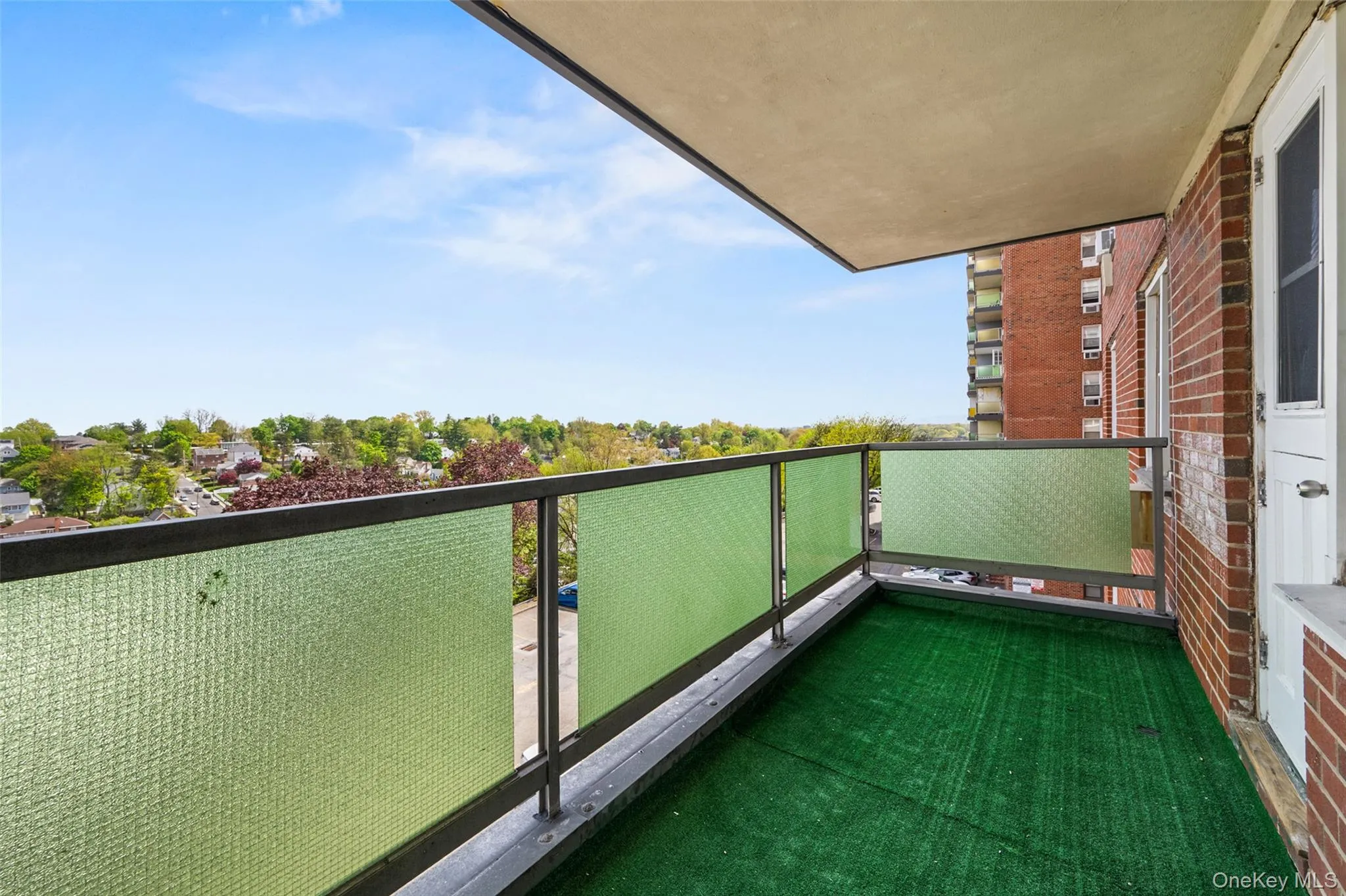 Balcony facing South East, featuring a green floor covering, privacy screens, and metal railing Balcony facing South East, featuring a green floor covering, privacy screens, and metal railing