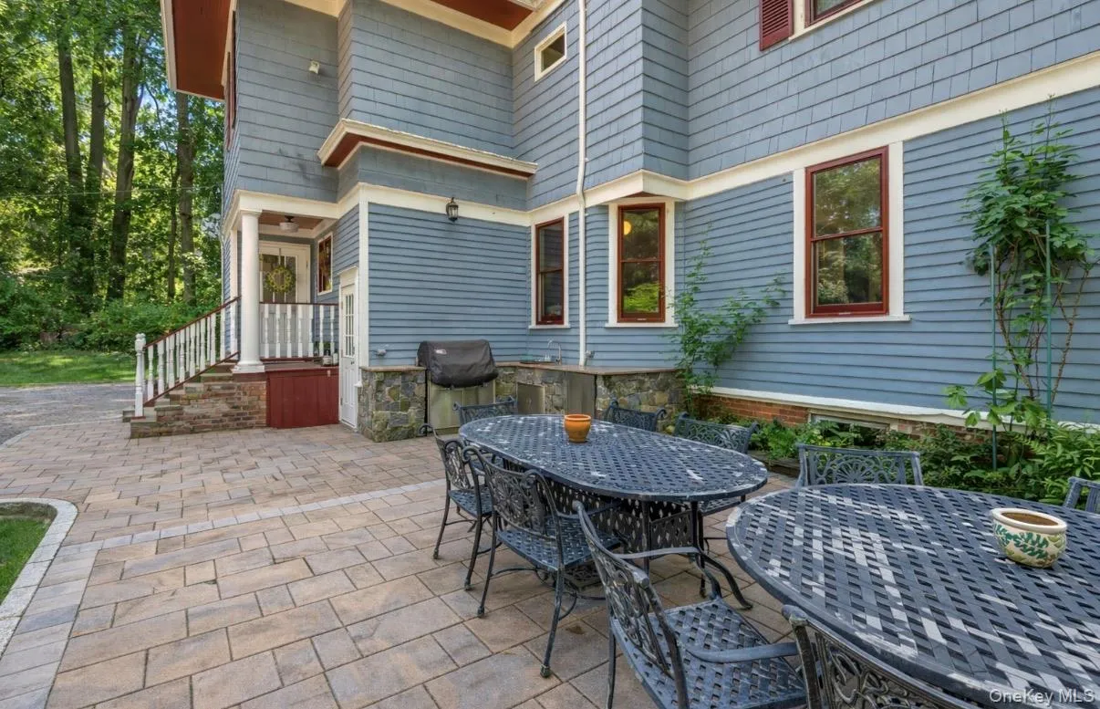 Expansive paver patio with a stone-clad outdoor kitchen area and a side entrance Expansive paver patio with a stone-clad outdoor kitchen area and a side entrance