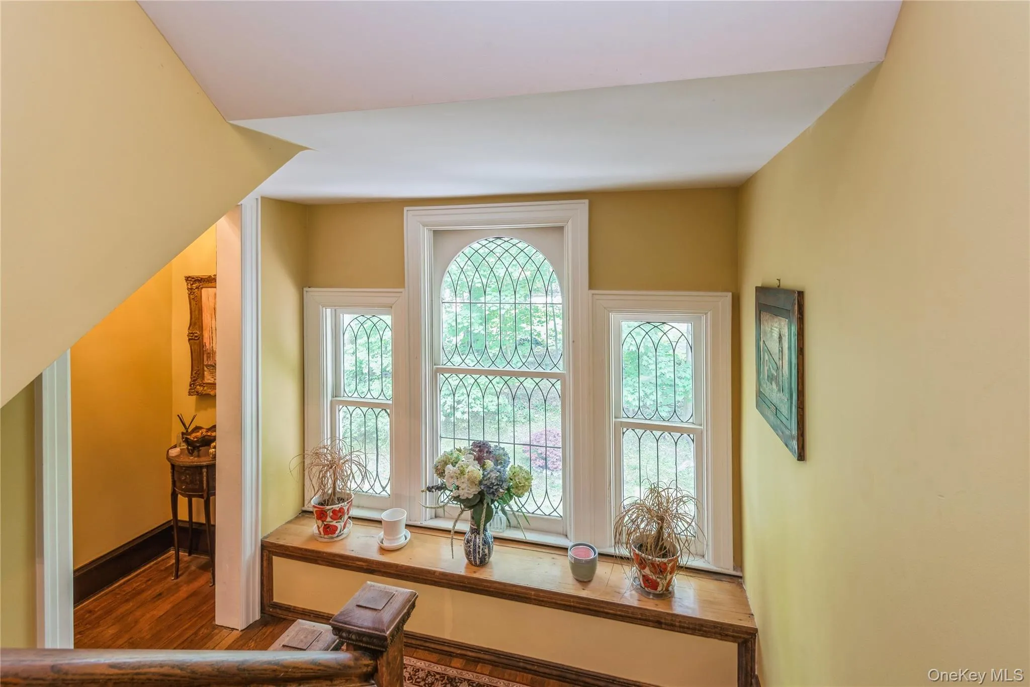 Ornate window alcove featuring three windows with decorative muntins, a central arched window, and a built-in wood window seat Ornate window alcove featuring three windows with decorative muntins, a central arched window, and a built-in wood window seat