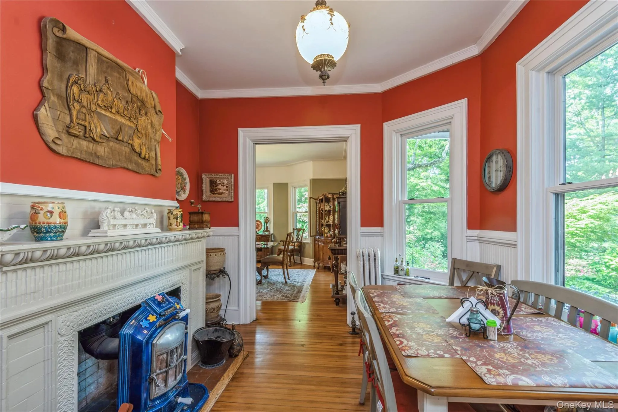 Breakfast room featuring hardwood flooring, white wainscoting, and a decorative fireplace Breakfast room featuring hardwood flooring, white wainscoting, and a decorative fireplace