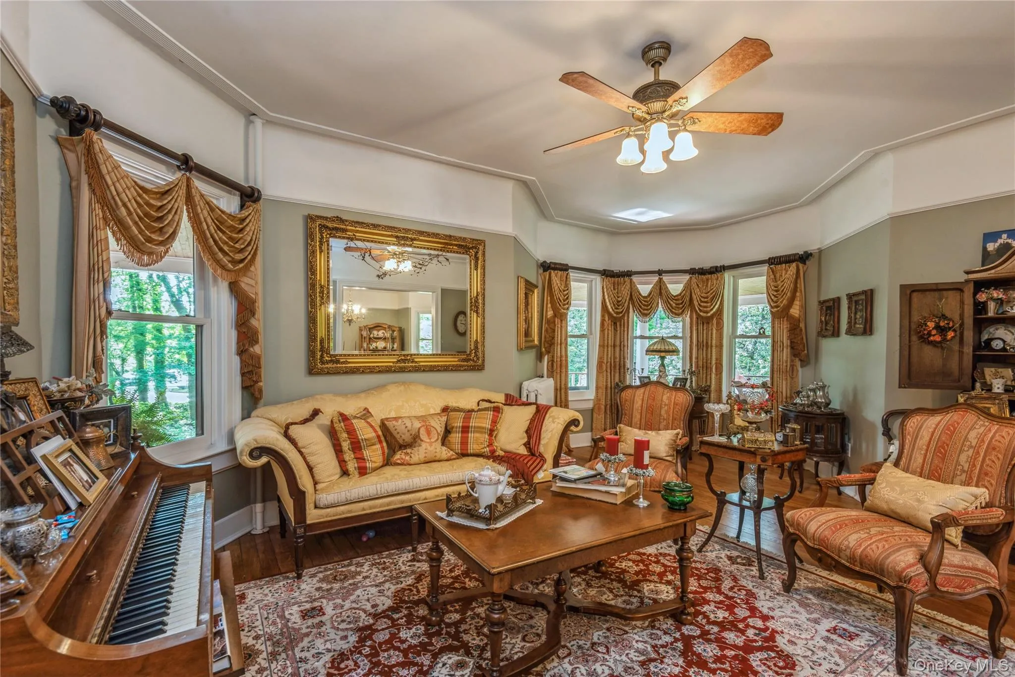 Formal living area featuring a bay window, wood-finish flooring, and a ceiling fan with integrated lighting Formal living area featuring a bay window, wood-finish flooring, and a ceiling fan with integrated lighting