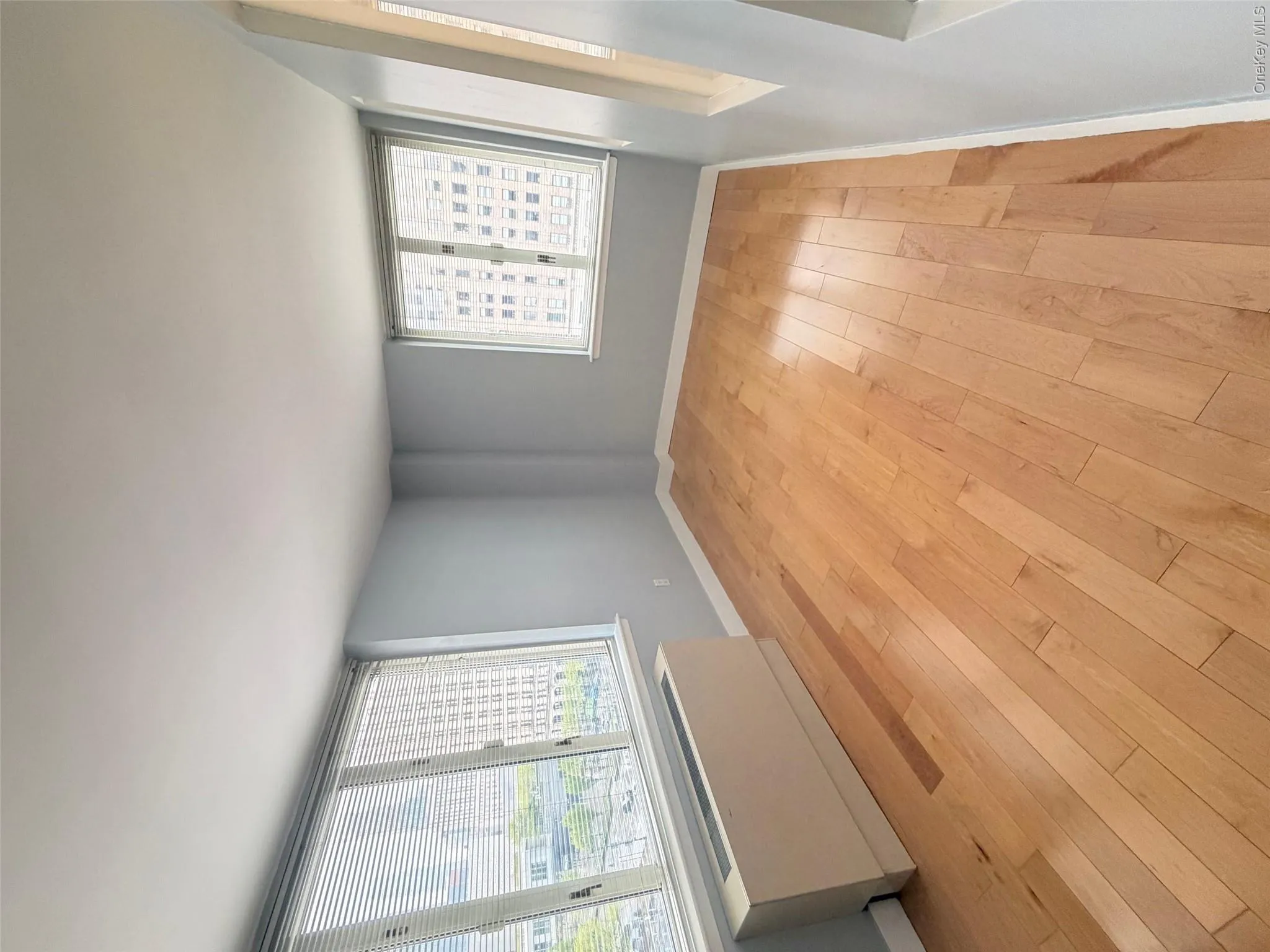 Light-filled interior featuring expansive wood-finish flooring, multiple windows with blinds, light blue painted walls, and white trim Light-filled interior featuring expansive wood-finish flooring, multiple windows with blinds, light blue painted walls, and white trim