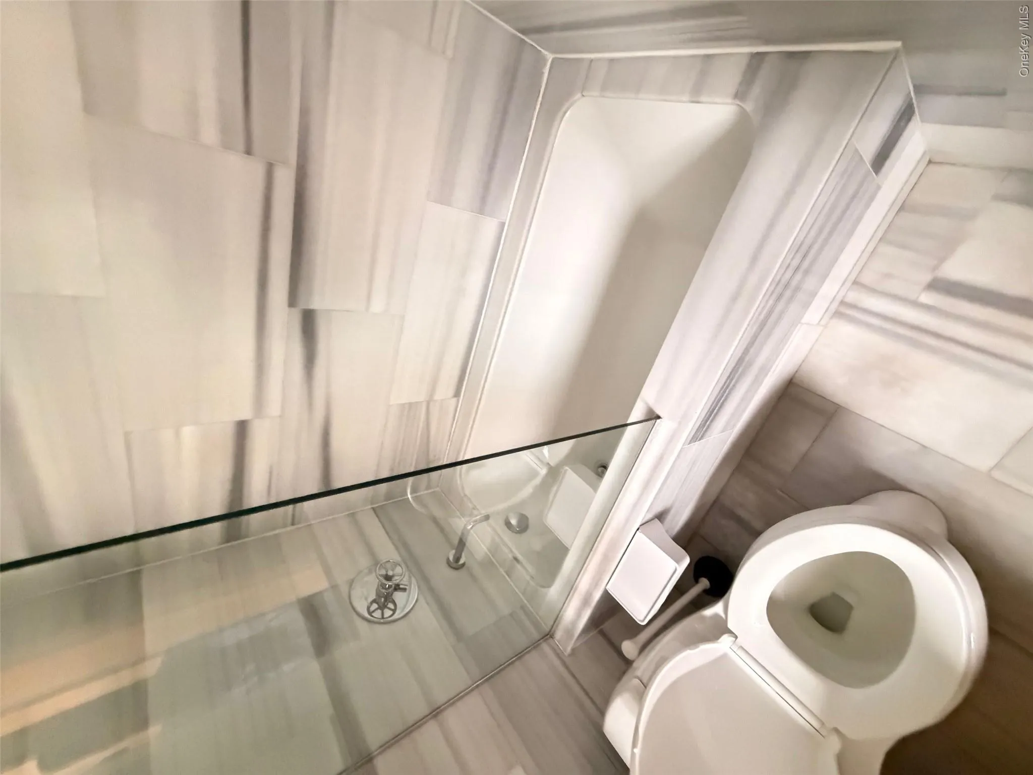 Bathroom featuring a white soaking tub with a glass shower enclosure and tiled surround Bathroom featuring a white soaking tub with a glass shower enclosure and tiled surround