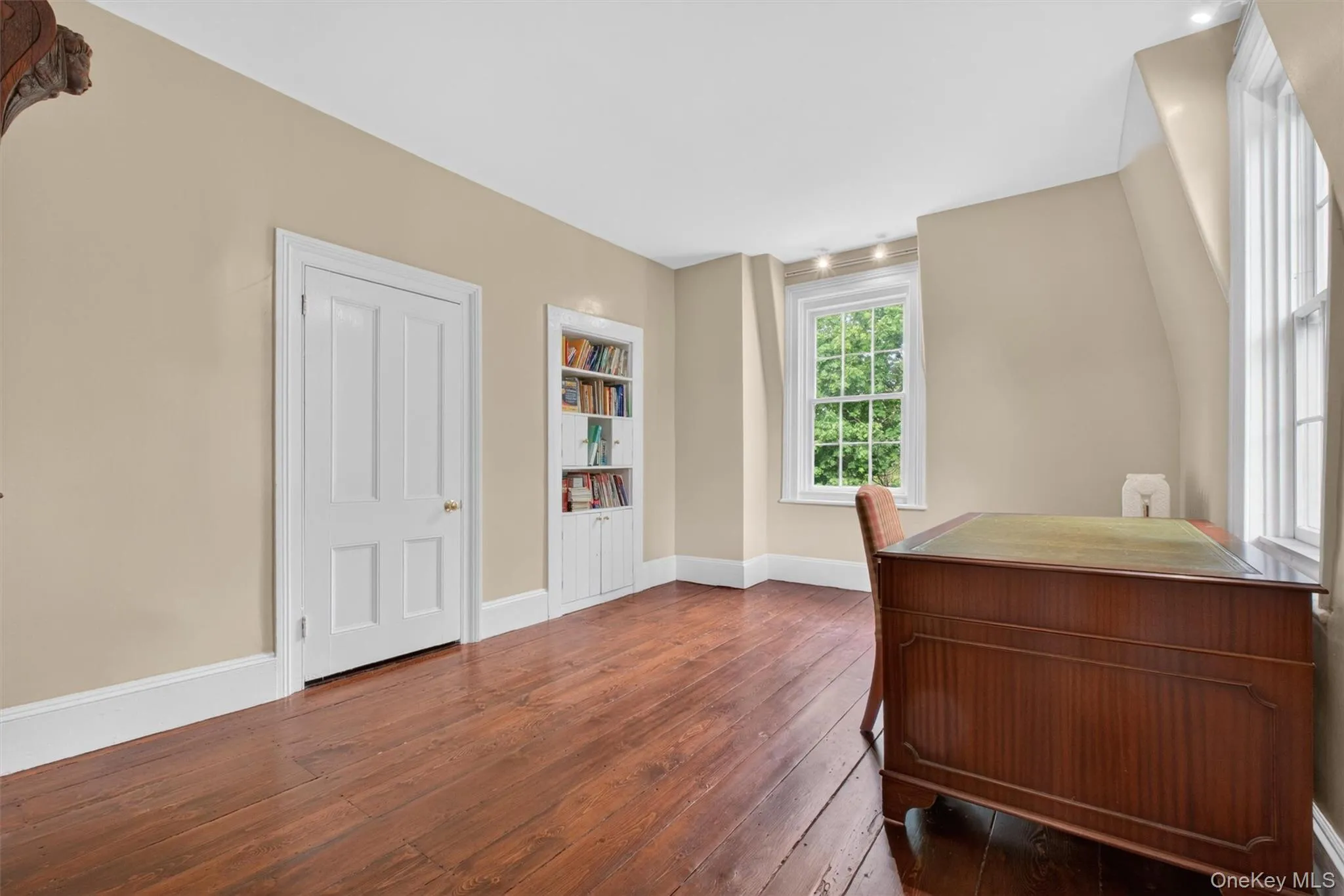 Room featuring wide-plank wood flooring, light-toned walls, white trim,closet, and large windows. Room featuring wide-plank wood flooring, light-toned walls, white trim,closet, and large windows.
