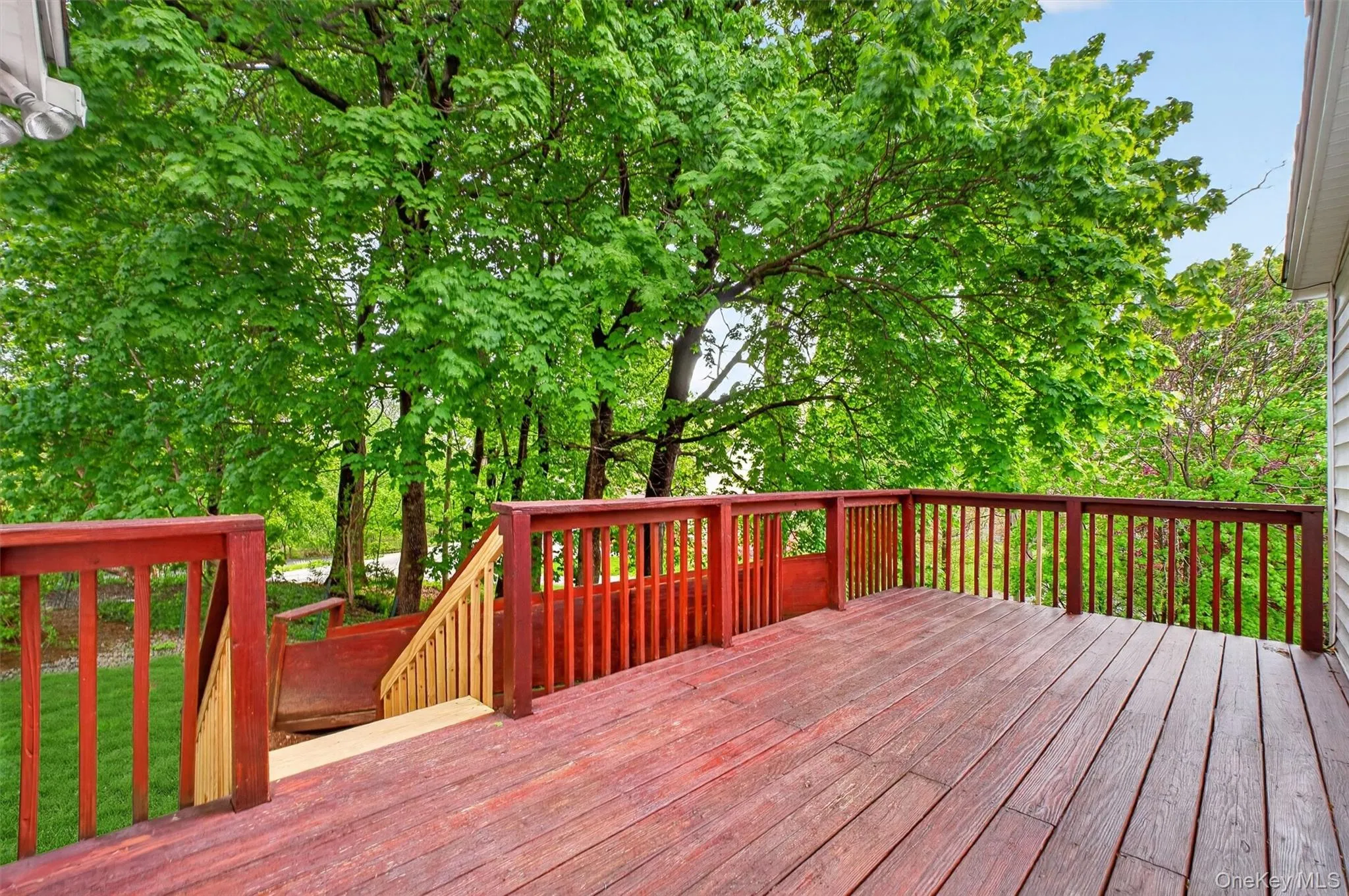 Spacious outdoor deck with wood flooring and matching railings, featuring a verdant tree canopy backdrop and integrated stairs. Spacious outdoor deck with wood flooring and matching railings, featuring a verdant tree canopy backdrop and integrated stairs.