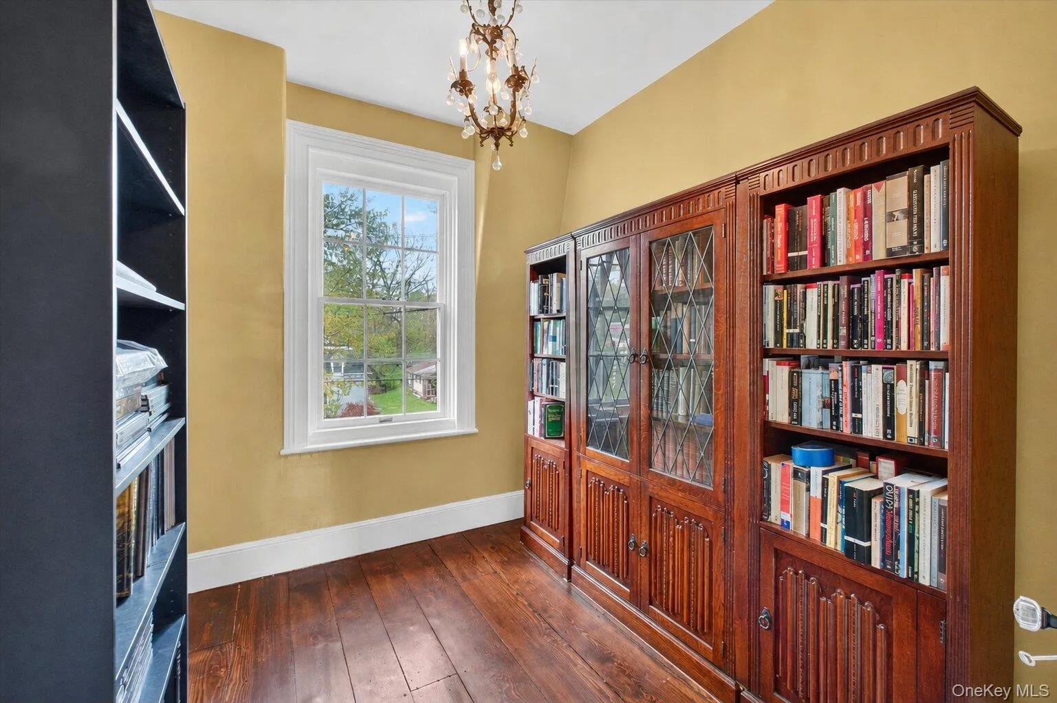 Room featuring wide-plank wood flooring, white trim, and a large window. Room featuring wide-plank wood flooring, white trim, and a large window.