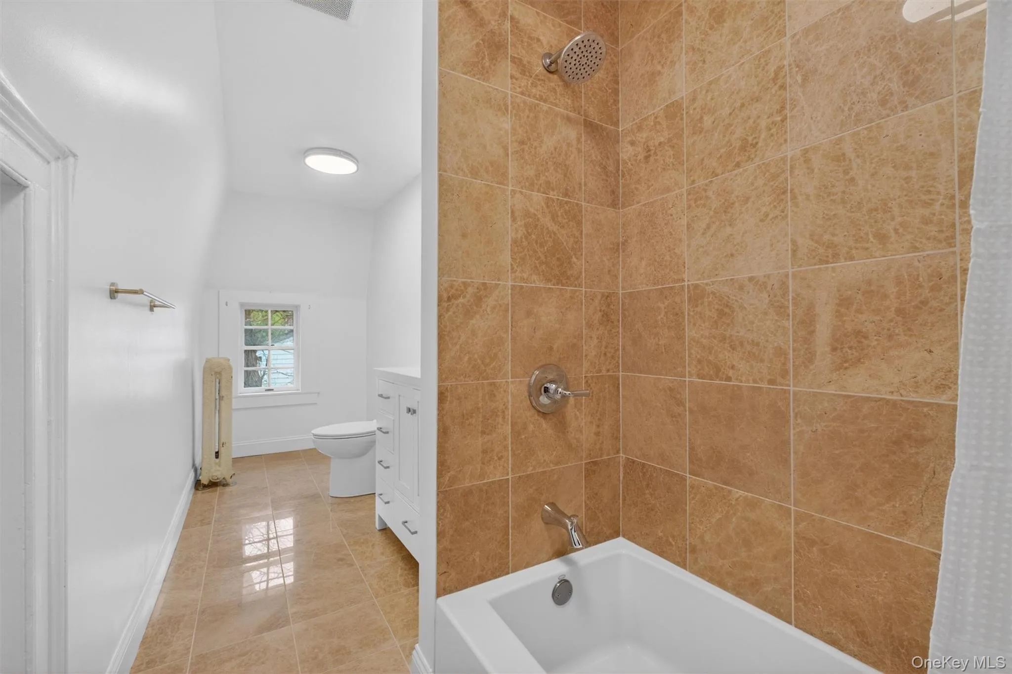 Bright bathroom featuring a tiled shower surround, integrated bathtub, and a modern vanity with cabinet storage Bright bathroom featuring a tiled shower surround, integrated bathtub, and a modern vanity with cabinet storage