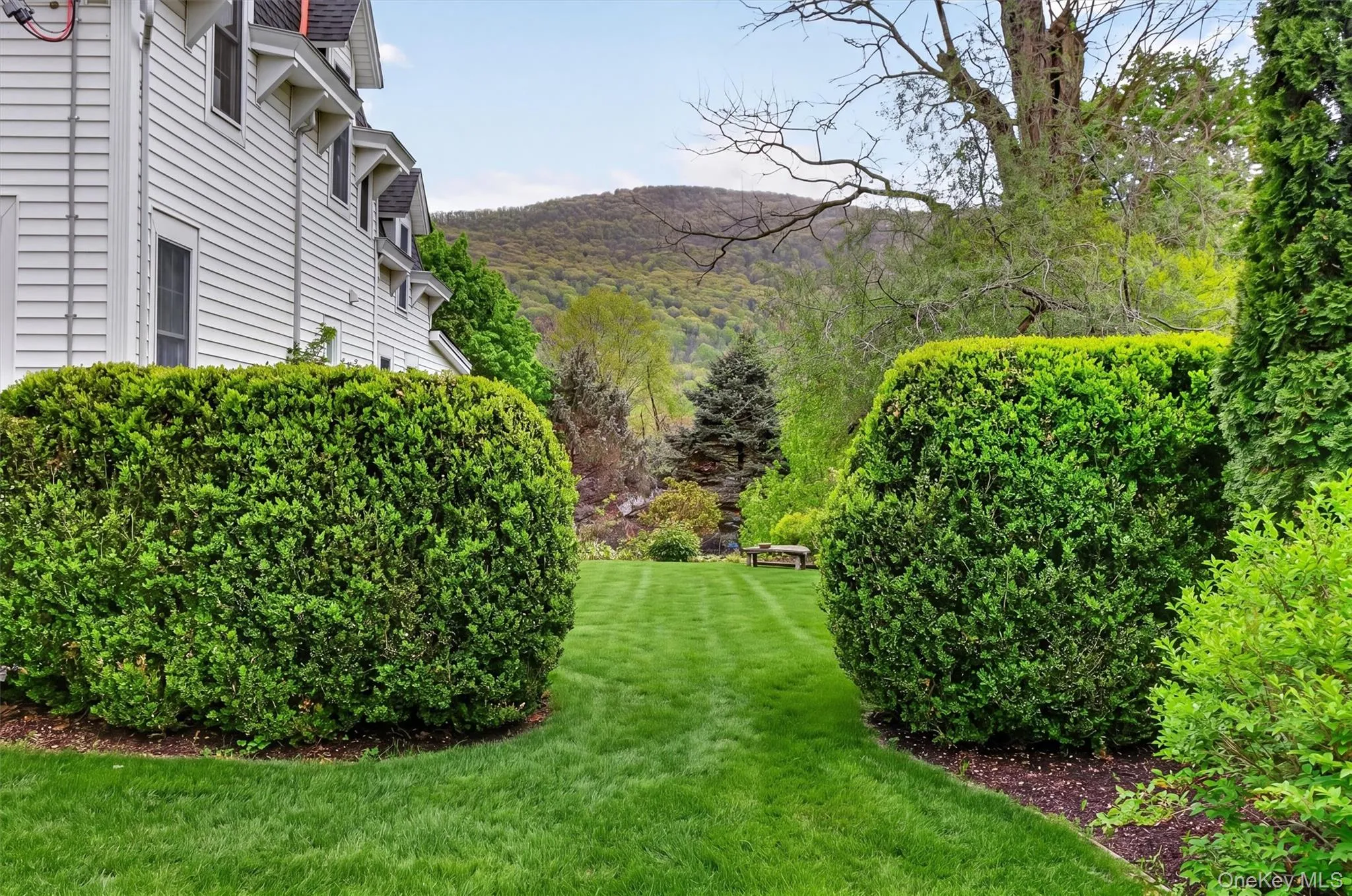 Expansive green lawn framed by manicured hedges leading to the backyard with views of the hills and mountain. Expansive green lawn framed by manicured hedges leading to the backyard with views of the hills and mountain.