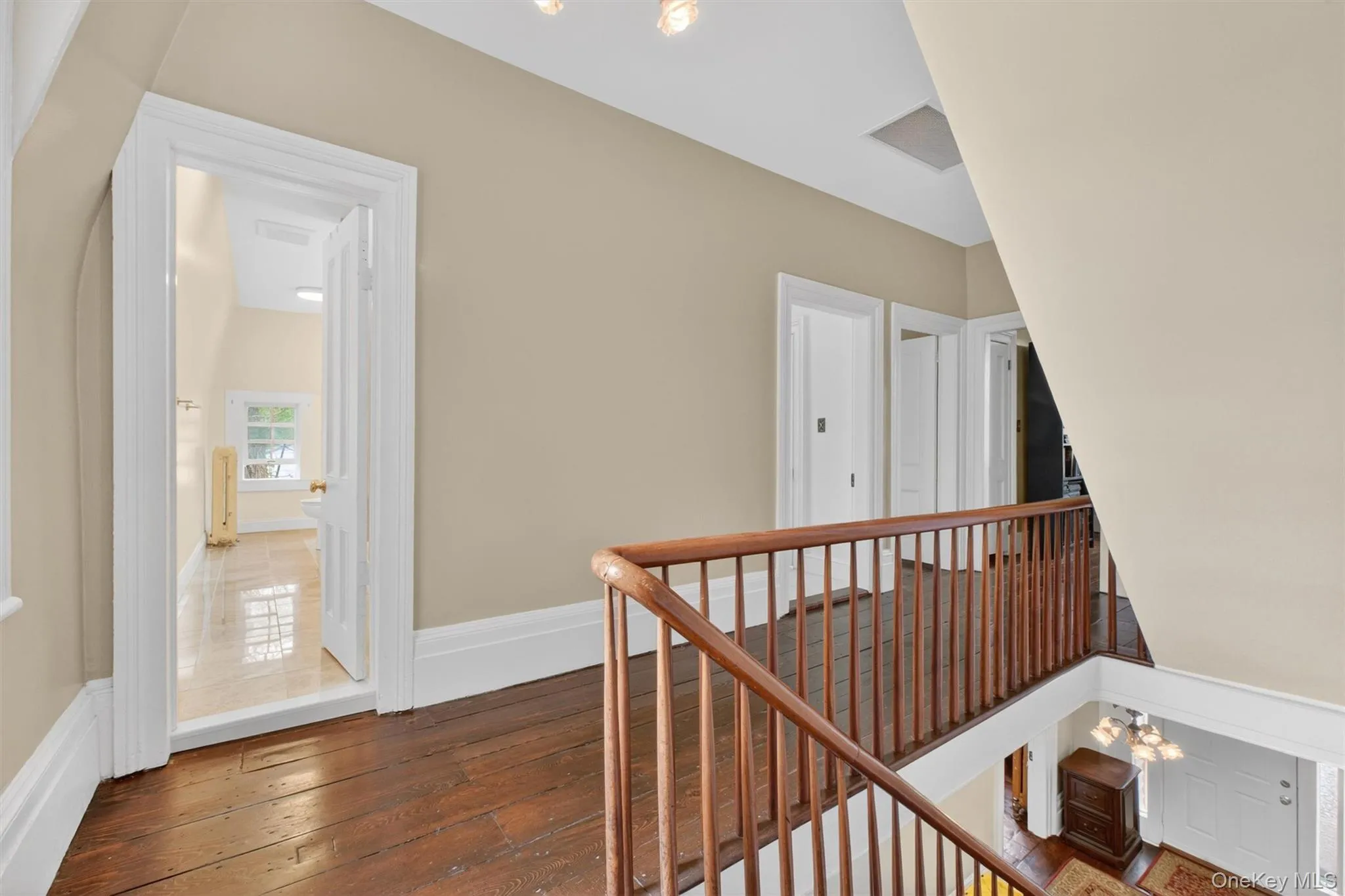 Second-story hallway featuring rich hardwood flooring, a classic wooden balustrade, and doors leading to other living areas. Second-story hallway featuring rich hardwood flooring, a classic wooden balustrade, and doors leading to other living areas.