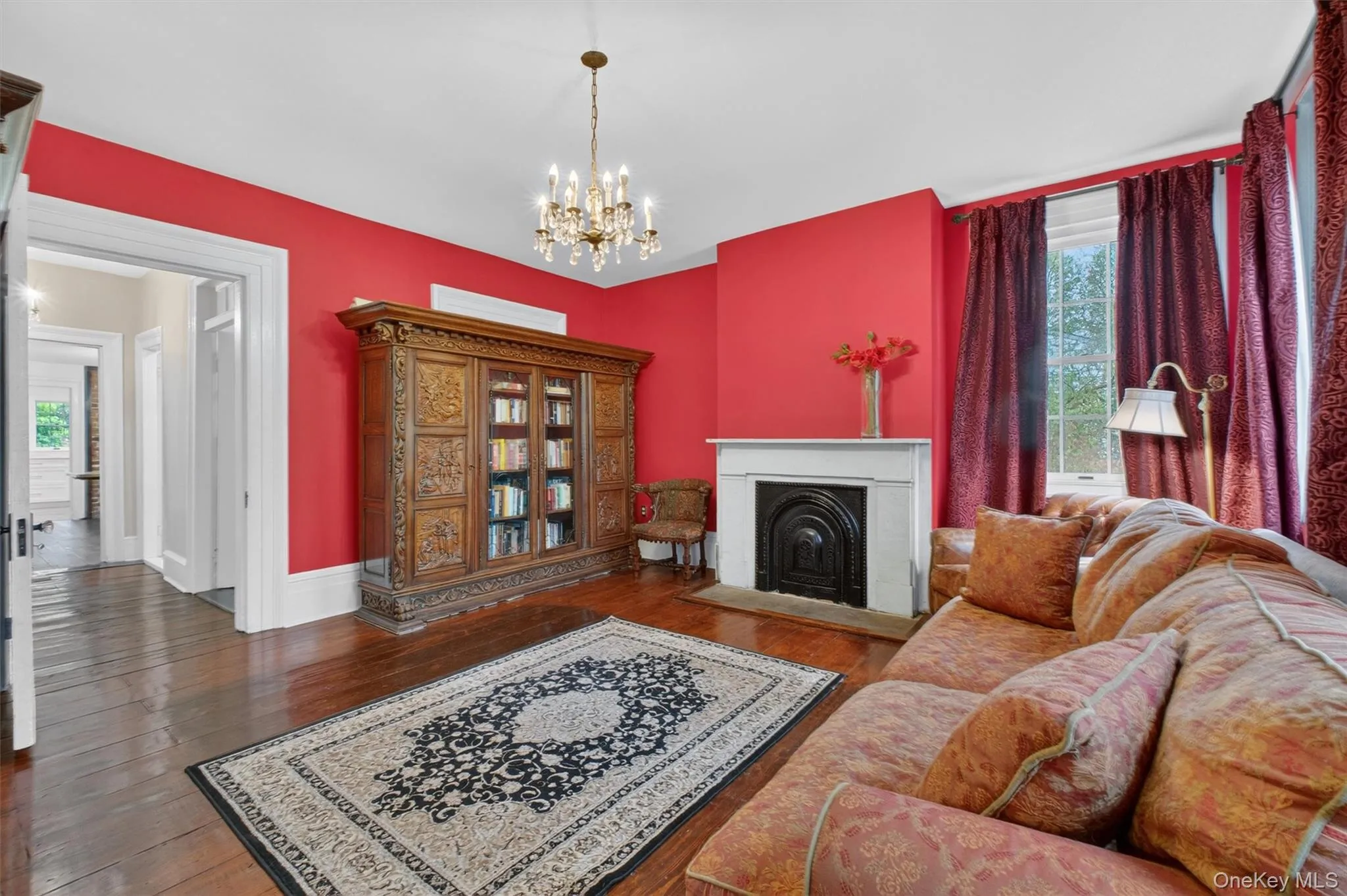 Hardwood flooring throughout, with a fireplace, large windows and doorway leading to other living areas Hardwood flooring throughout, with a fireplace, large windows and doorway leading to other living areas