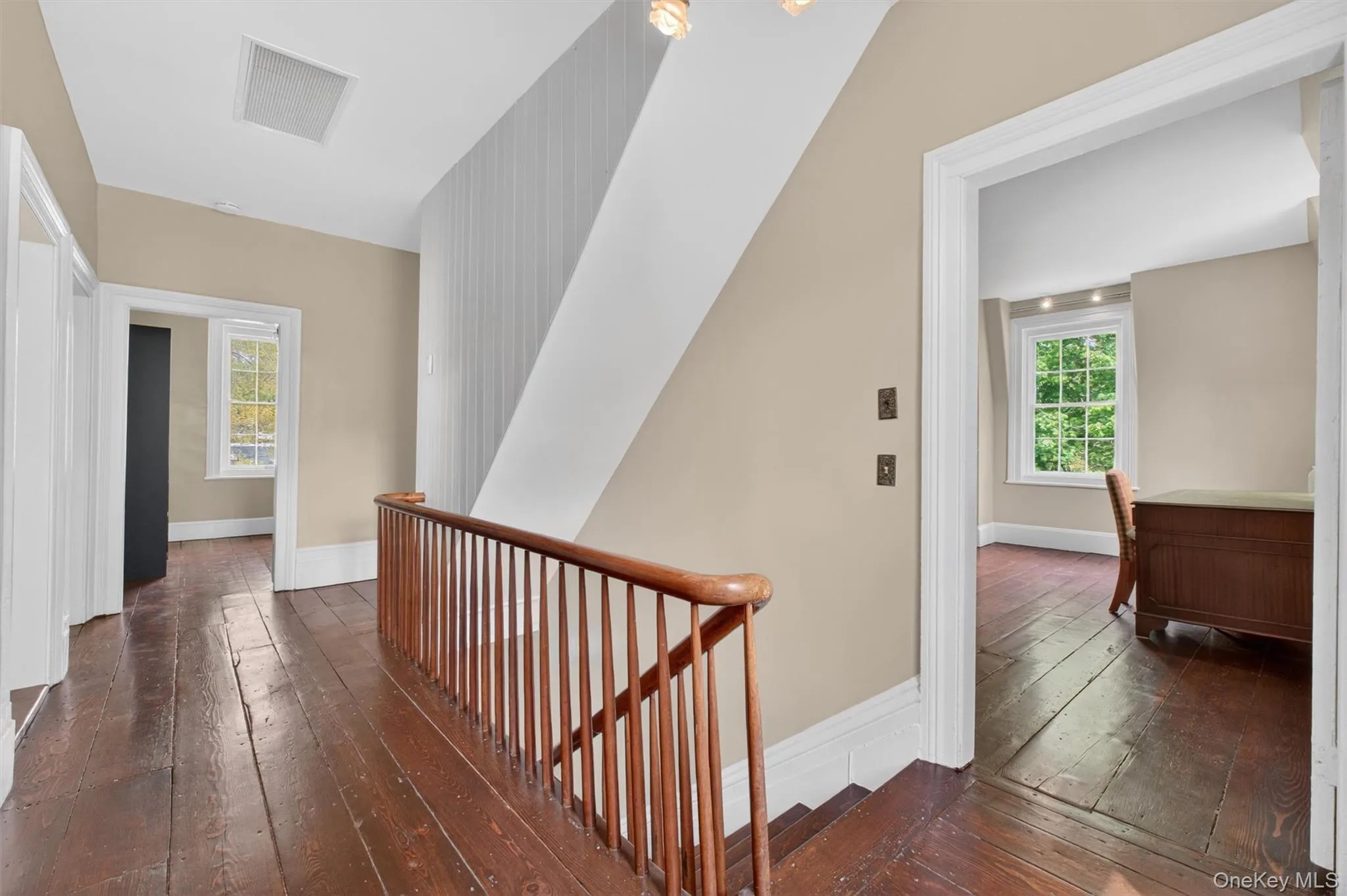 Second-story hallway featuring rich hardwood flooring, a classic wooden balustrade, and doors leading to other living areas. Second-story hallway featuring rich hardwood flooring, a classic wooden balustrade, and doors leading to other living areas.