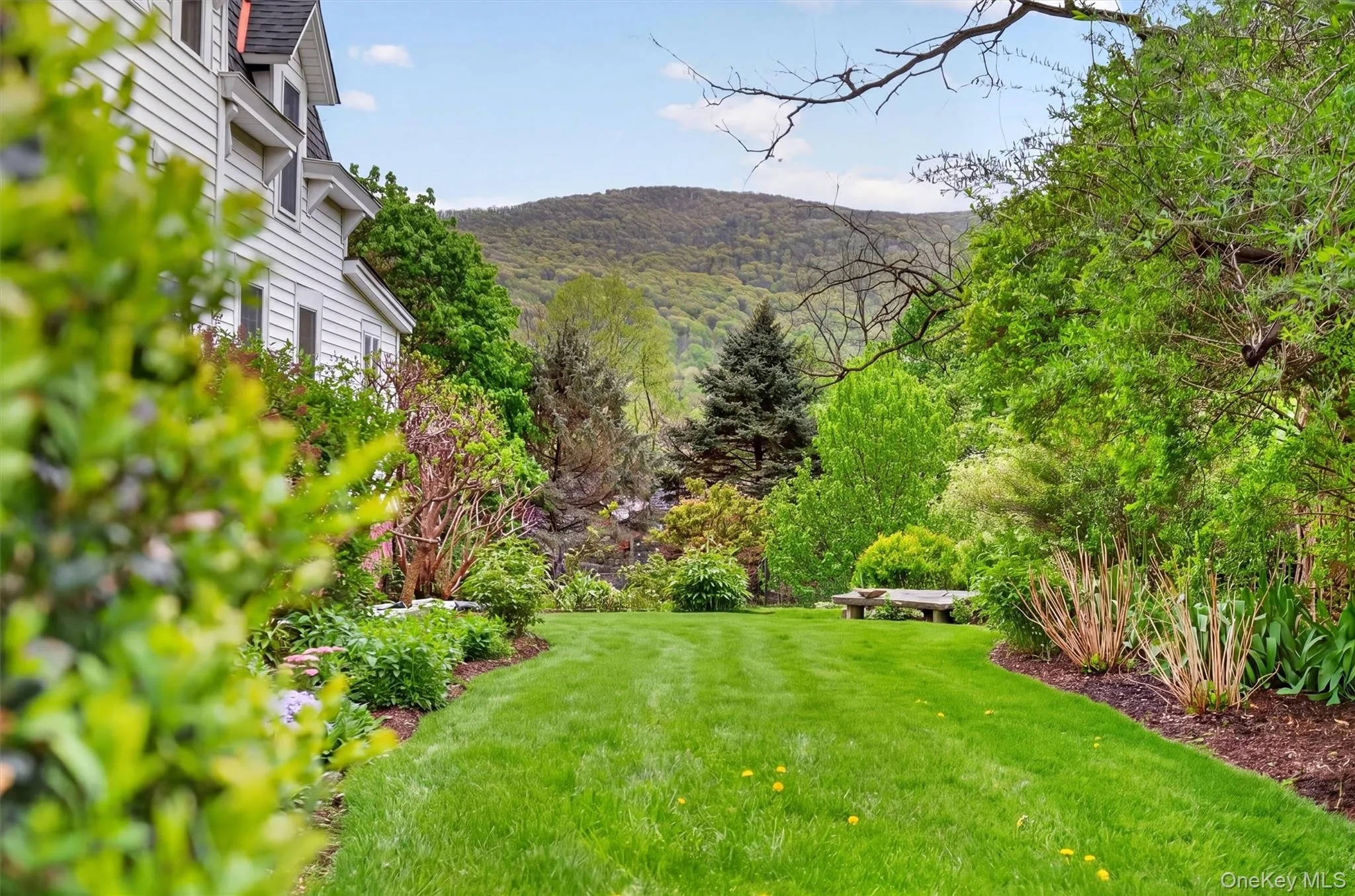 Expansive green lawn framed by manicured hedges leading to the backyard with views of the hills and mountain. Expansive green lawn framed by manicured hedges leading to the backyard with views of the hills and mountain.