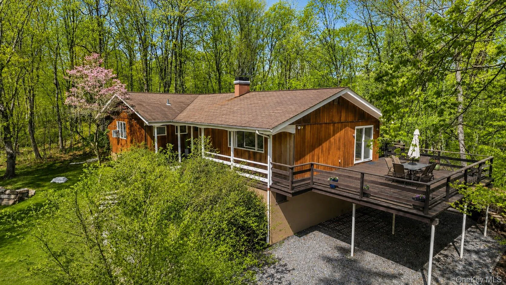 A stunning aerial view reveals this unique home featuring an expansive wraparound deck surrounded by nature. A stunning aerial view reveals this unique home featuring an expansive wraparound deck surrounded by nature.