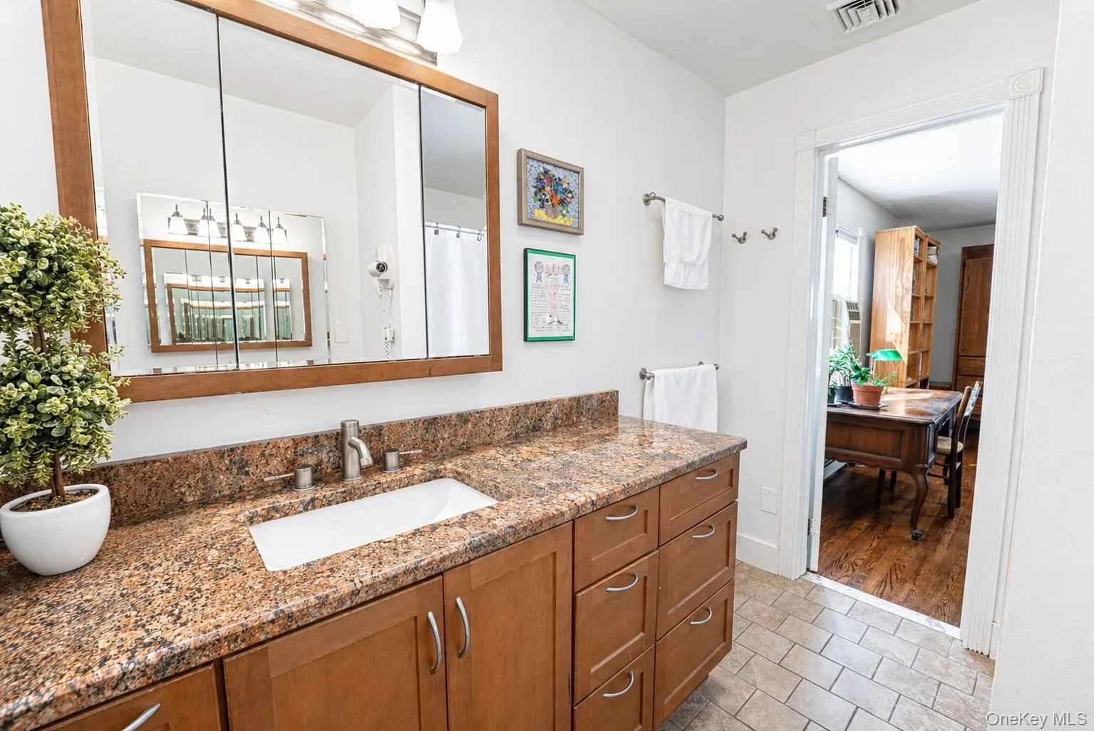 An en-suite bath off the primary bedroom features a spacious vanity and oversized mirror. An en-suite bath off the primary bedroom features a spacious vanity and oversized mirror.