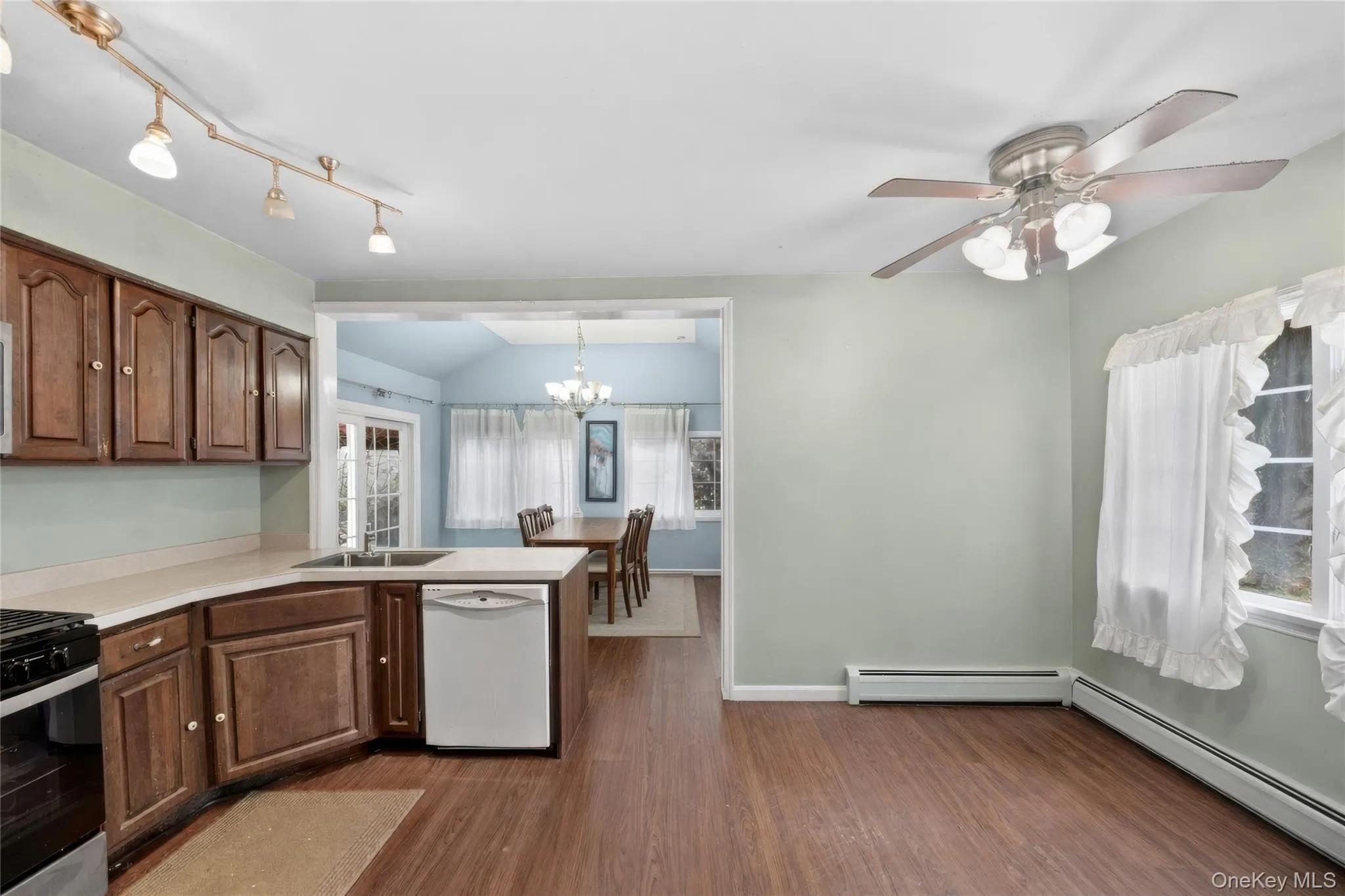 Kitchen space featuring wood-finish flooring, warm wood cabinetry, and a white dishwasher Kitchen space featuring wood-finish flooring, warm wood cabinetry, and a white dishwasher