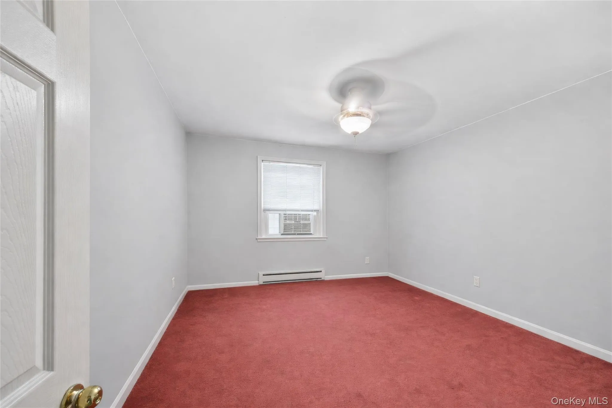 Spacious room with red carpet flooring, white painted walls, and a ceiling fan with integrated lighting Spacious room with red carpet flooring, white painted walls, and a ceiling fan with integrated lighting