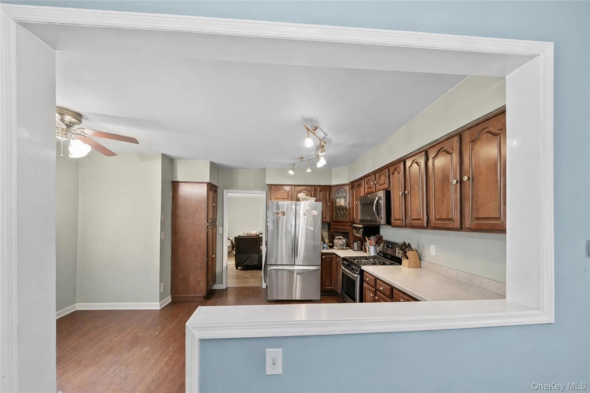 Kitchen with wood cabinetry, light-toned countertops, and stainless steel appliances Kitchen with wood cabinetry, light-toned countertops, and stainless steel appliances