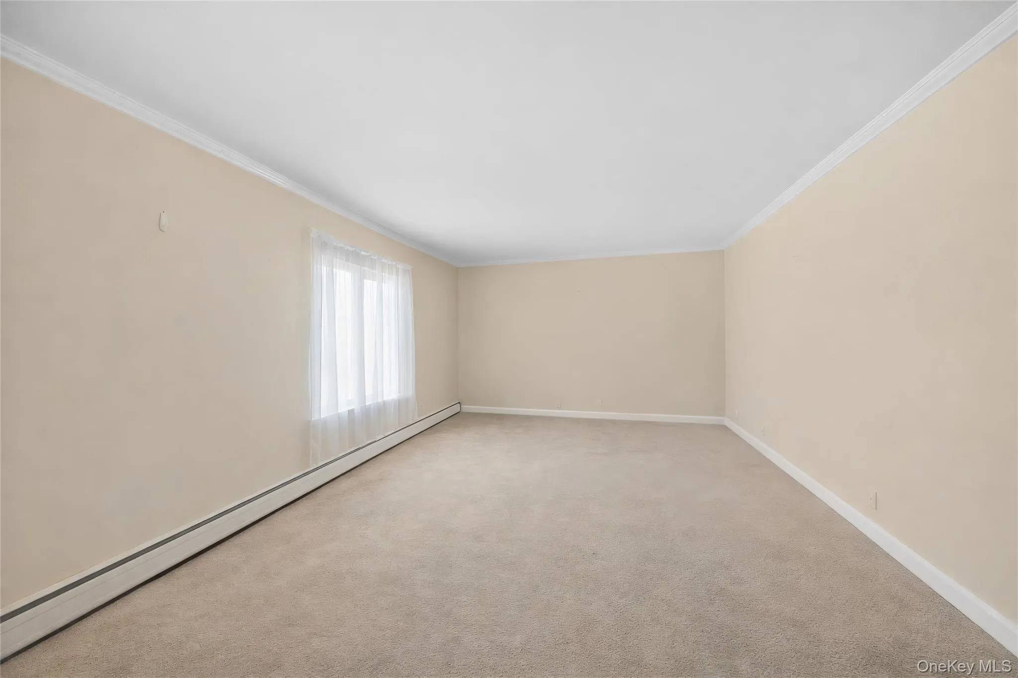 Spacious room featuring neutral carpeting and light beige walls Spacious room featuring neutral carpeting and light beige walls