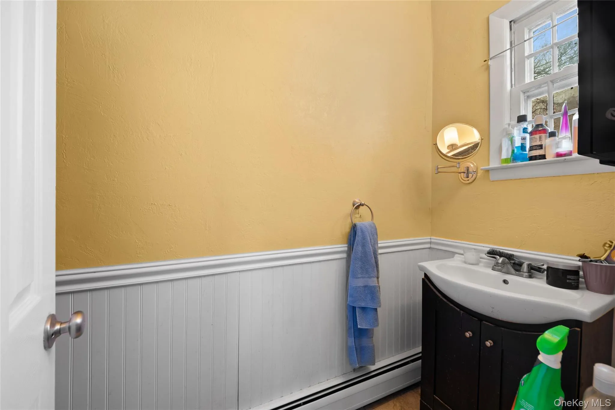 Bathroom featuring a dark wood-finish vanity with an integrated sink, polished chrome faucet, and white beadboard wainscoting Bathroom featuring a dark wood-finish vanity with an integrated sink, polished chrome faucet, and white beadboard wainscoting