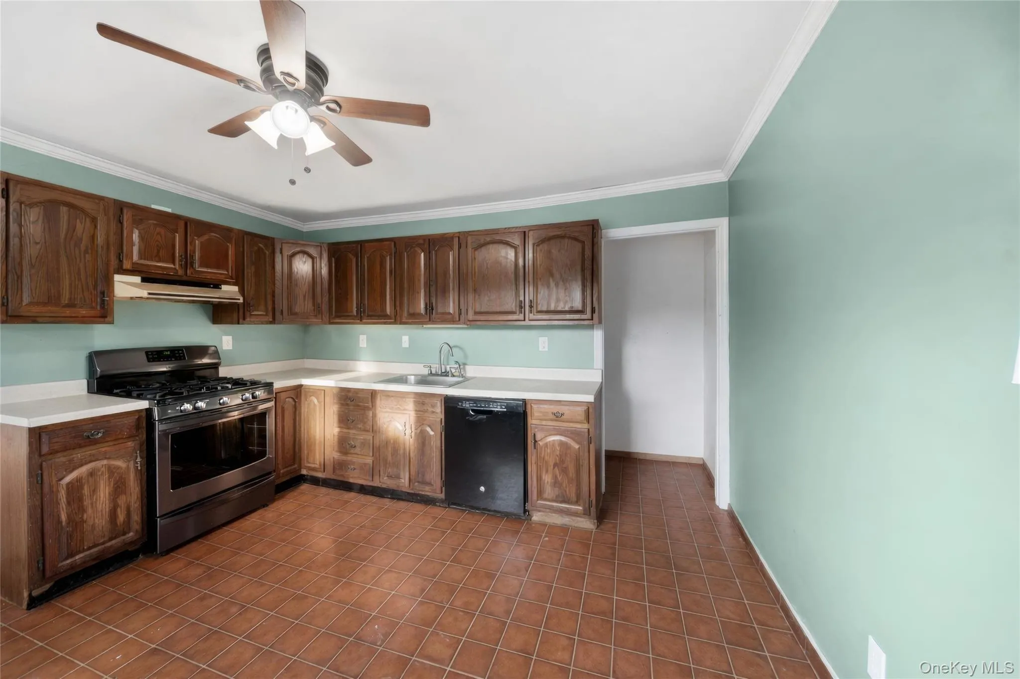Kitchen featuring abundant wood cabinetry, light countertops, a stainless steel range, and tile flooring Kitchen featuring abundant wood cabinetry, light countertops, a stainless steel range, and tile flooring