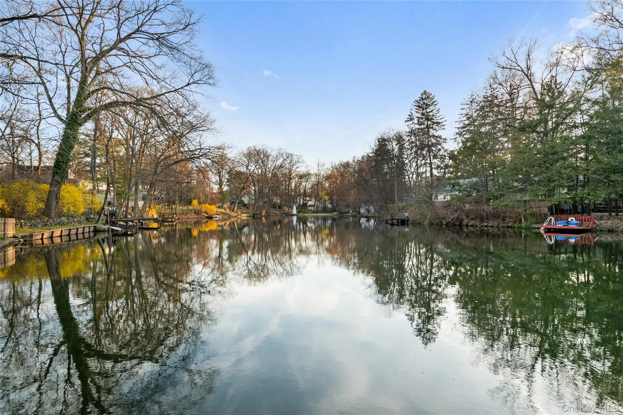 Serene waterfront setting featuring calm water reflecting trees and sky Serene waterfront setting featuring calm water reflecting trees and sky