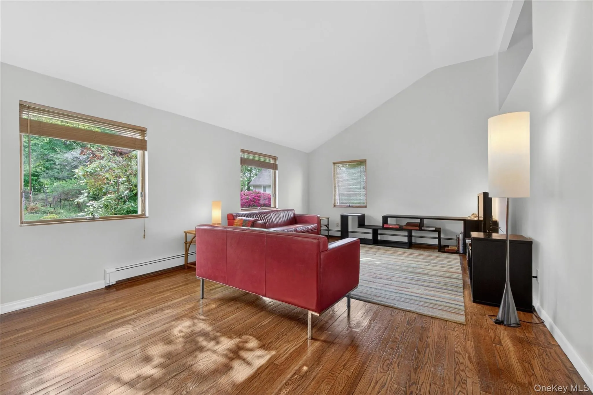 The expansive living room features newly refinished hardwood floors, abundant natural light, and a soaring vaulted ceiling. The expansive living room features newly refinished hardwood floors, abundant natural light, and a soaring vaulted ceiling.