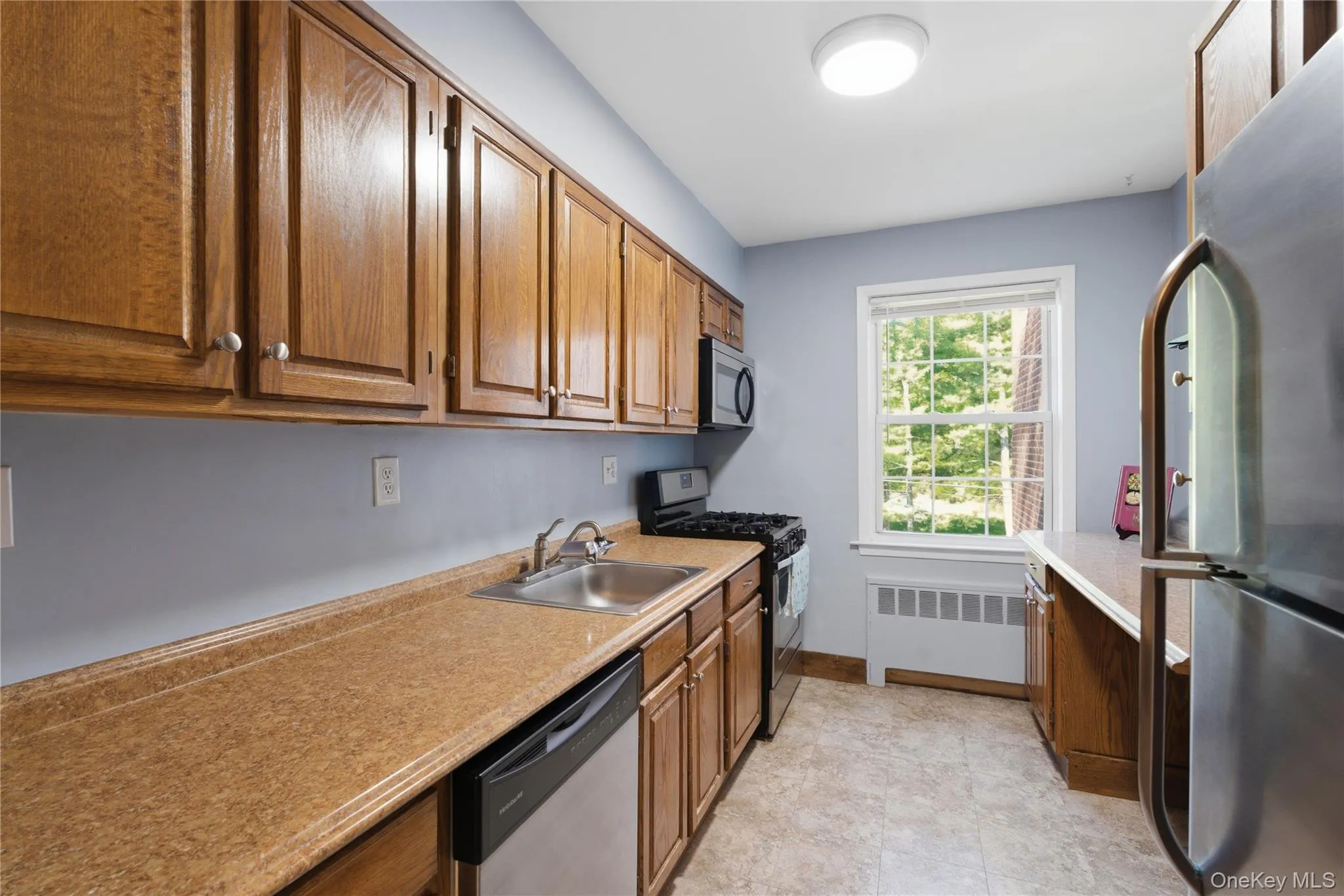 Kitchen featuring ample wood cabinetry, a stainless steel sink and a built-in dishwasher Kitchen featuring ample wood cabinetry, a stainless steel sink and a built-in dishwasher