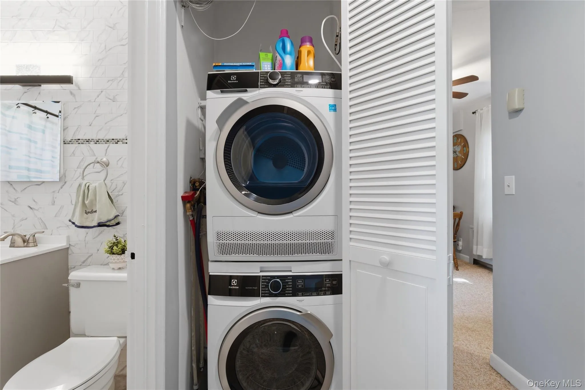 New stacked front-loading washer and dryer set, integrated into a louvered bi-fold closet in the hallway next to the bathroom New stacked front-loading washer and dryer set, integrated into a louvered bi-fold closet in the hallway next to the bathroom