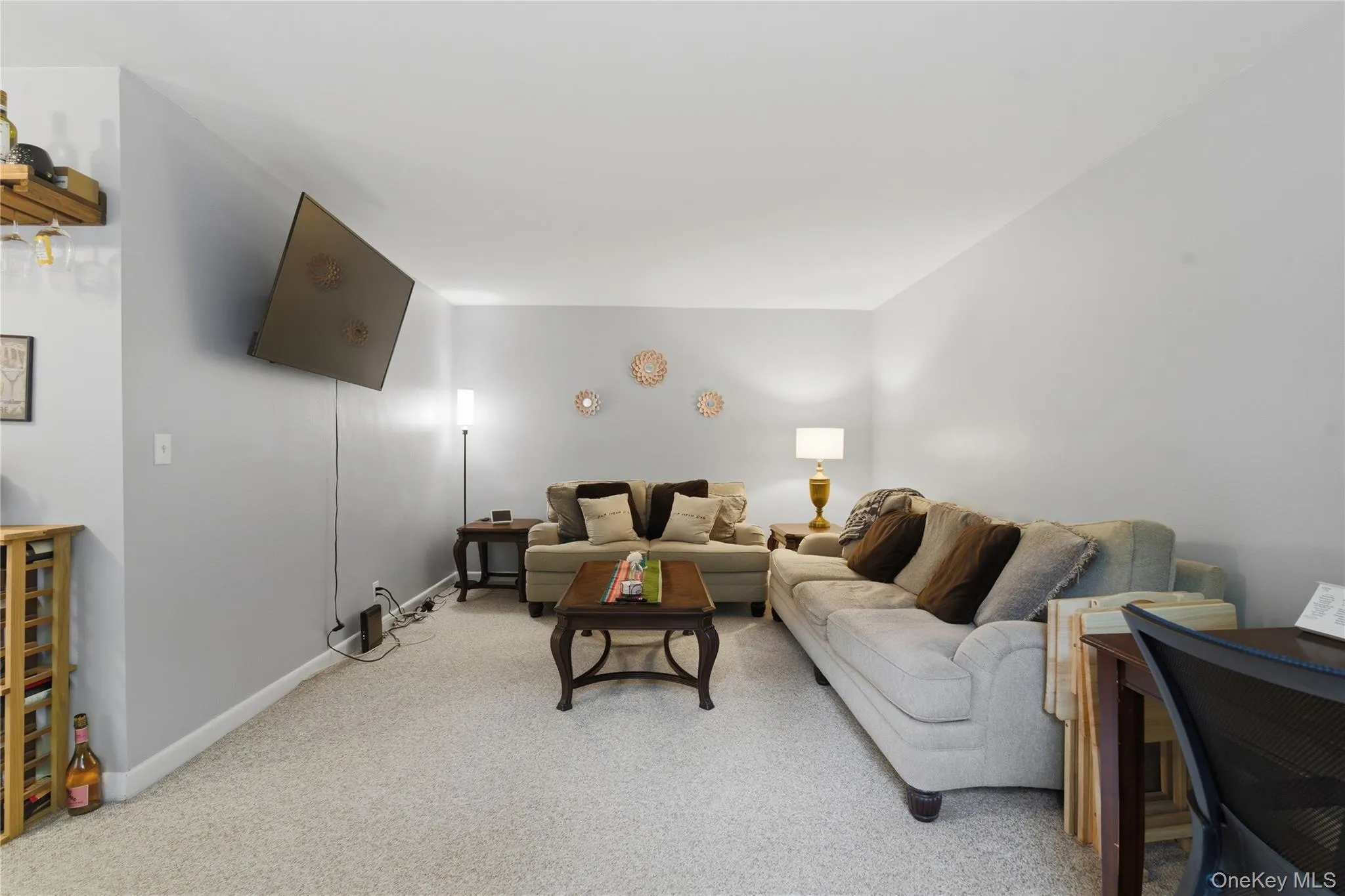 Large living room, carpeted with light gray wall paint and white baseboards Large living room, carpeted with light gray wall paint and white baseboards
