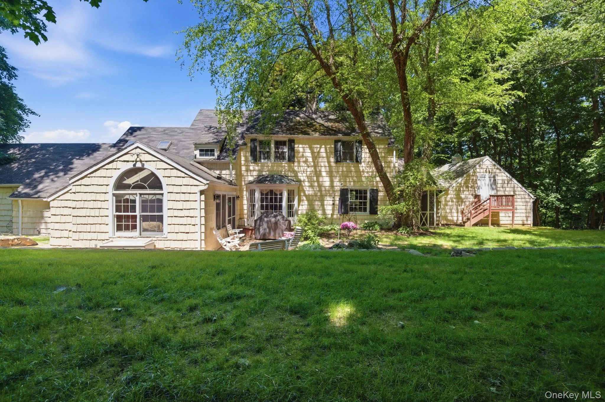 The rear of this Chappaqua Colonial showcases the family room addition, screened porch, and a generous backyard set against a private wooded backdrop. The rear of this Chappaqua Colonial showcases the family room addition, screened porch, and a generous backyard set against a private wooded backdrop.