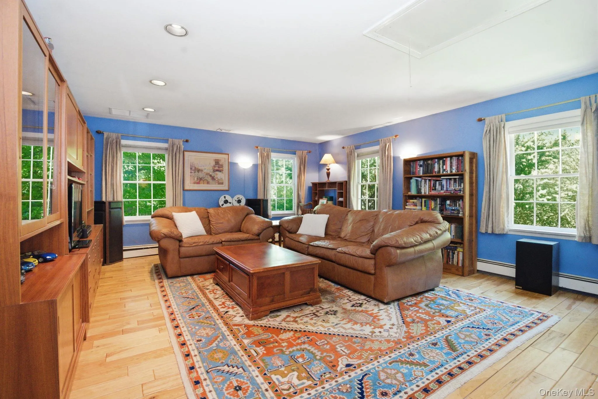 The generous proportions and tree-framed windows of this first-floor primary suite make it a versatile space that works as a bedroom, den, or both. The generous proportions and tree-framed windows of this first-floor primary suite make it a versatile space that works as a bedroom, den, or both.