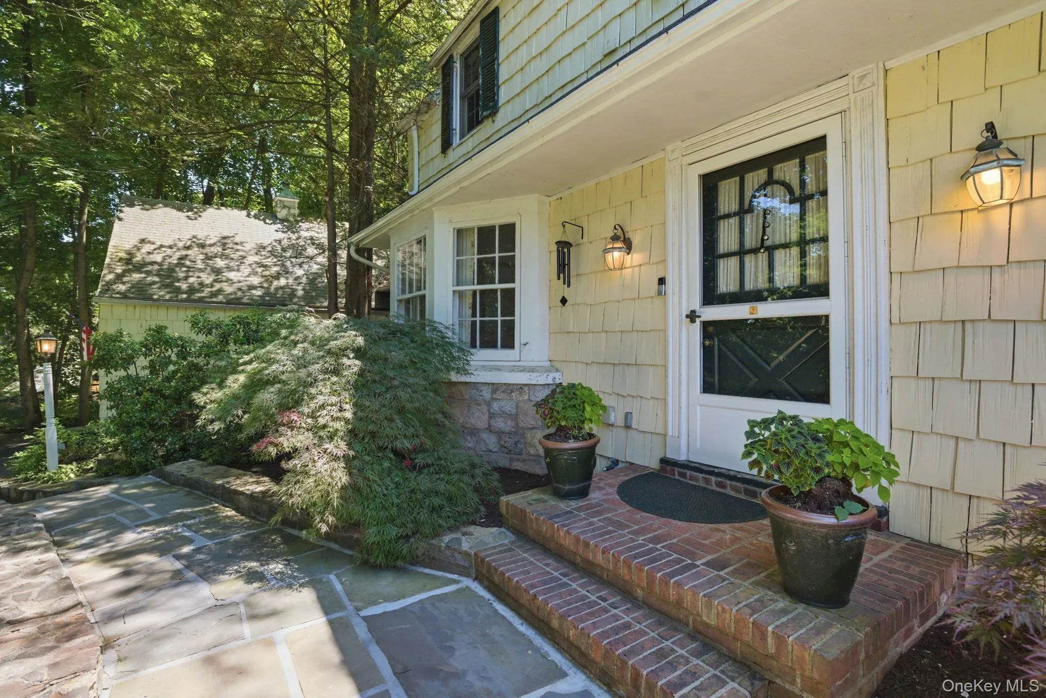 The covered entry and flagstone path connect the front door to the 2-car garage on this private Chappaqua corner lot. The covered entry and flagstone path connect the front door to the 2-car garage on this private Chappaqua corner lot.