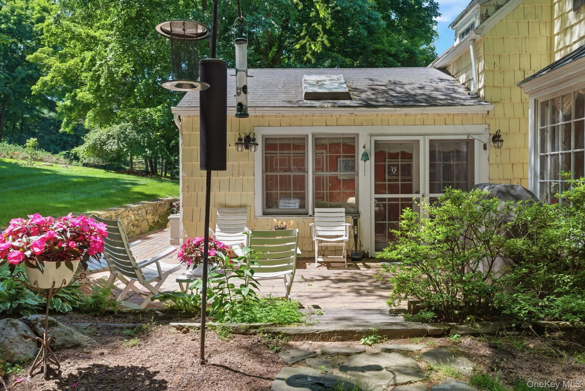 The rear deck and family room addition sit surrounded by mature plantings and a flagstone path leading through the yard. The rear deck and family room addition sit surrounded by mature plantings and a flagstone path leading through the yard.