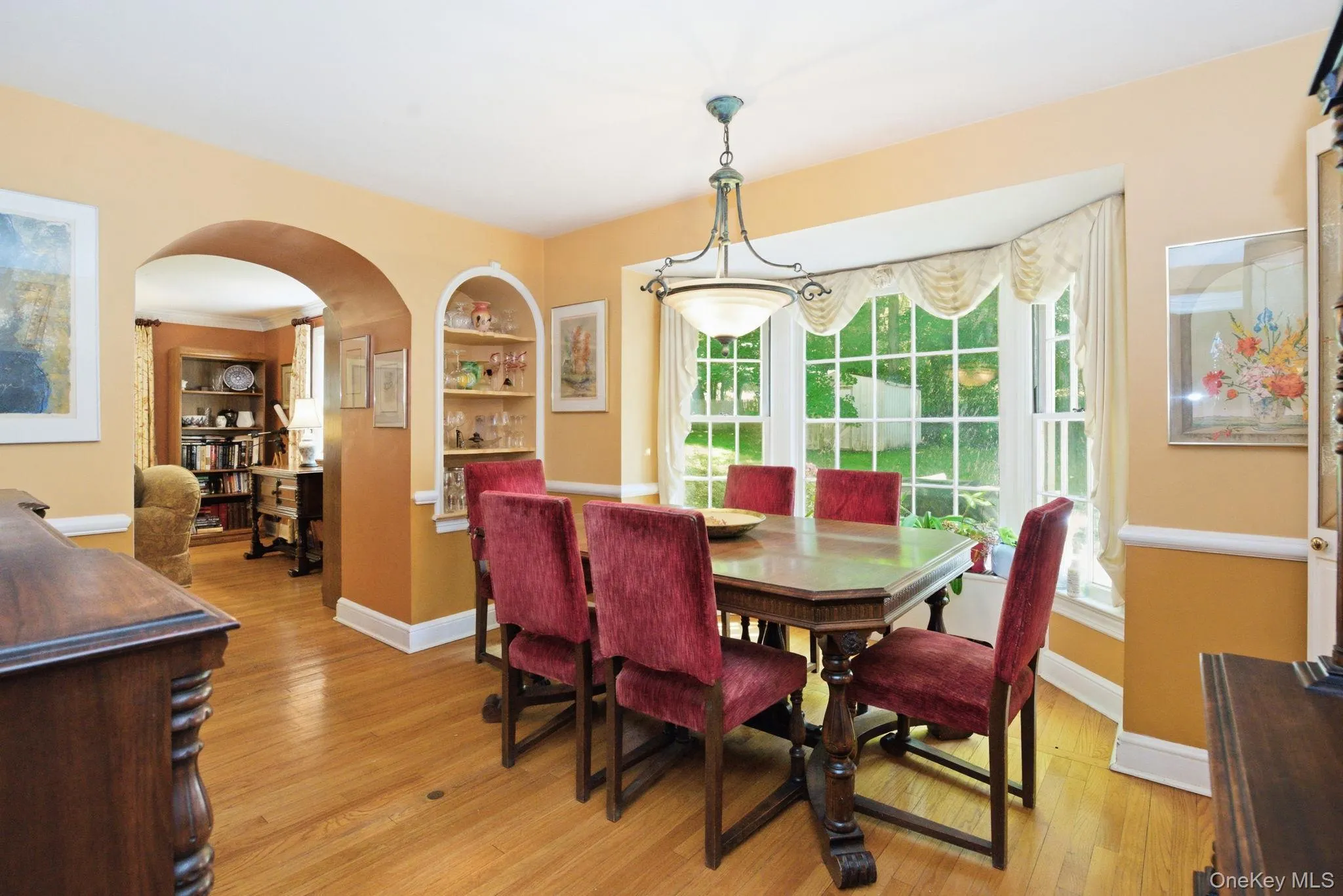 The formal dining room features hardwood floors, built-in arched shelving, a bay window, and an open flow to the living room, family room, and kitchen. The formal dining room features hardwood floors, built-in arched shelving, a bay window, and an open flow to the living room, family room, and kitchen.