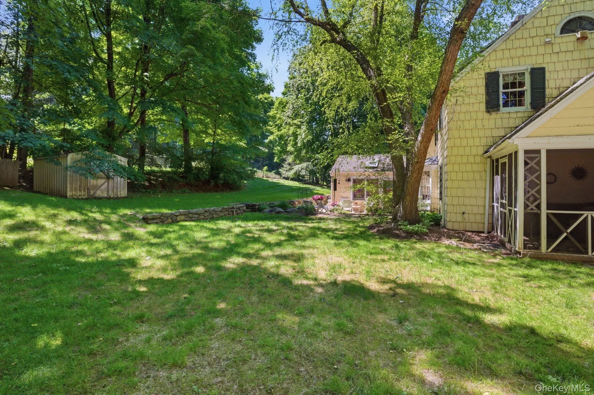 The private setting on nearly three-quarters of an acre includes a screened porch, stone wall, and mature trees framing the yard on all sides. The private setting on nearly three-quarters of an acre includes a screened porch, stone wall, and mature trees framing the yard on all sides.