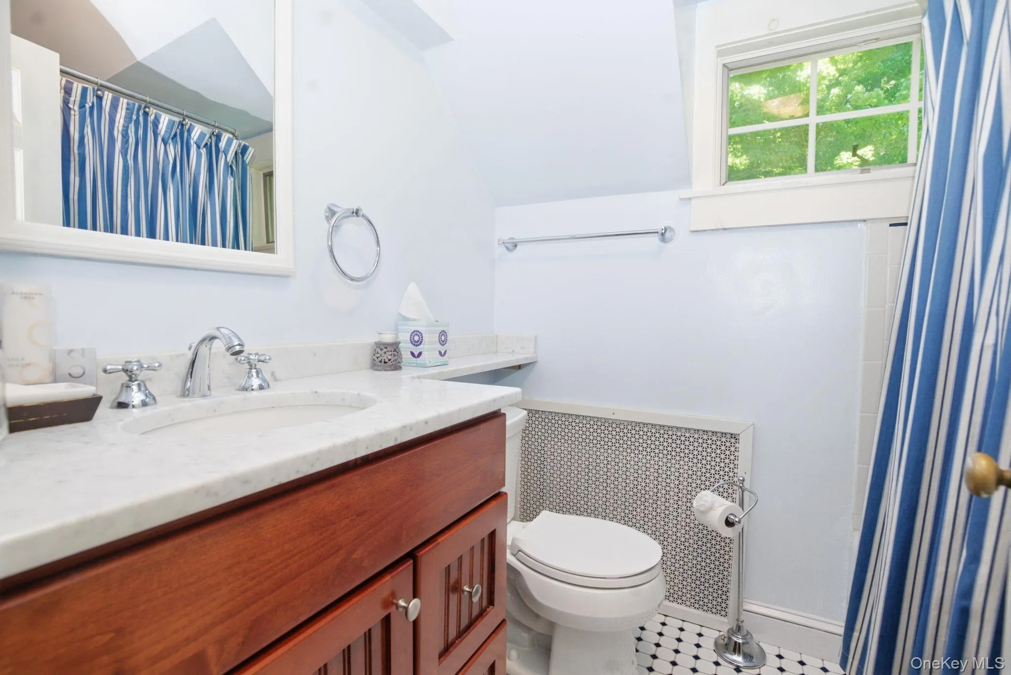 The full hall bathroom features a marble vanity top, wood cabinetry, classic tile floor, and a tub/shower combination. The full hall bathroom features a marble vanity top, wood cabinetry, classic tile floor, and a tub/shower combination.