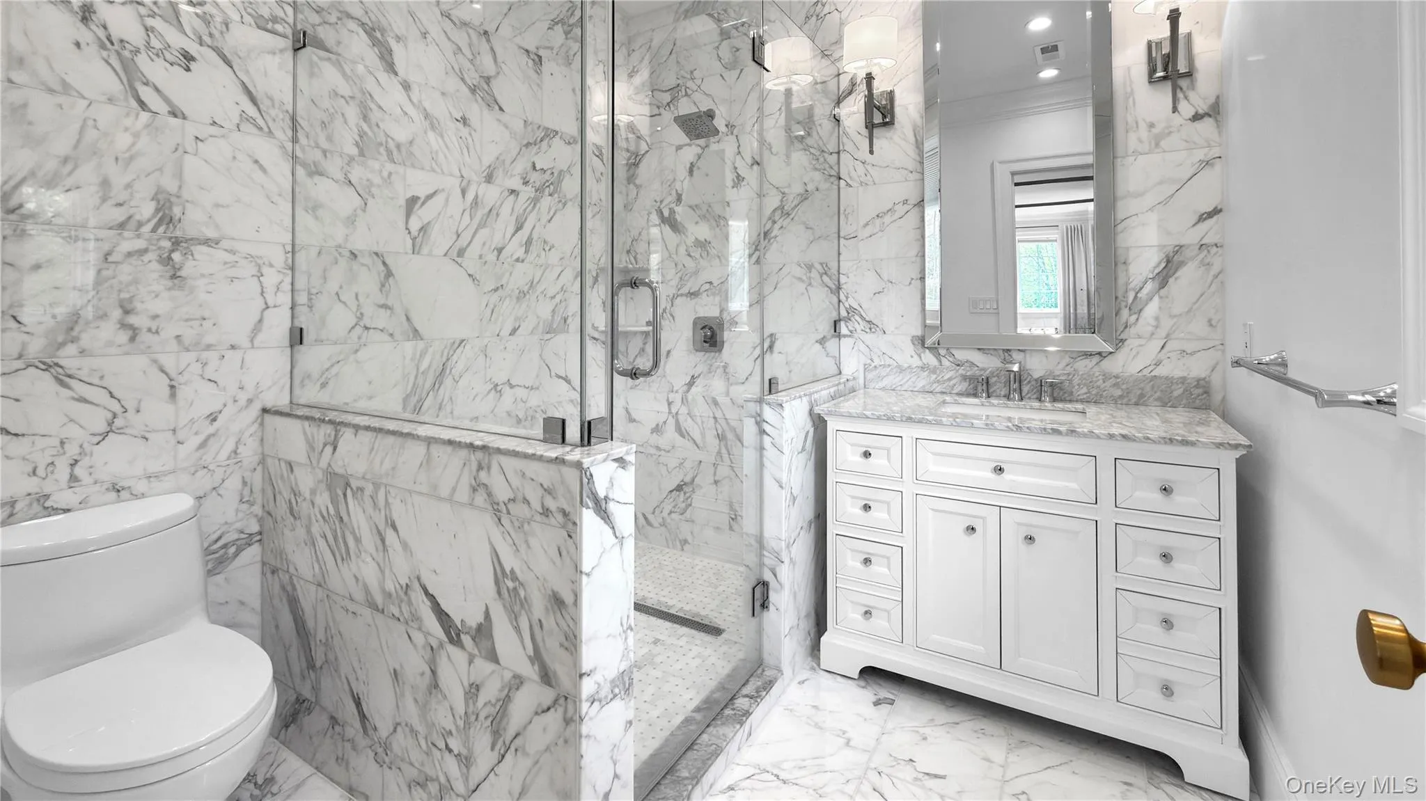 Bathroom featuring full-height marble-look tile walls, frameless glass shower enclosure, and a white vanity with a light-toned countertop Bathroom featuring full-height marble-look tile walls, frameless glass shower enclosure, and a white vanity with a light-toned countertop